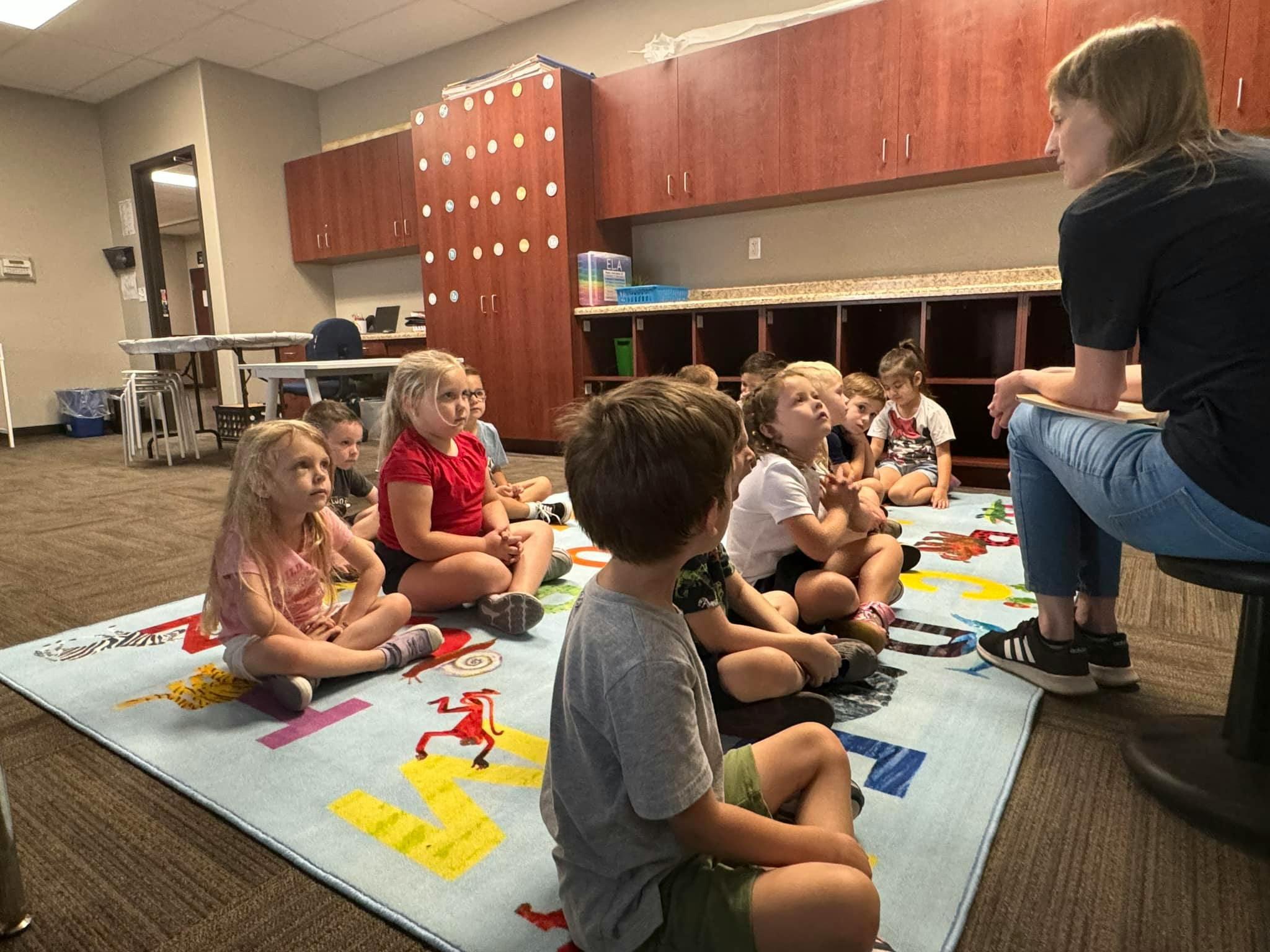Adult and children sitting on a rug in a classroom