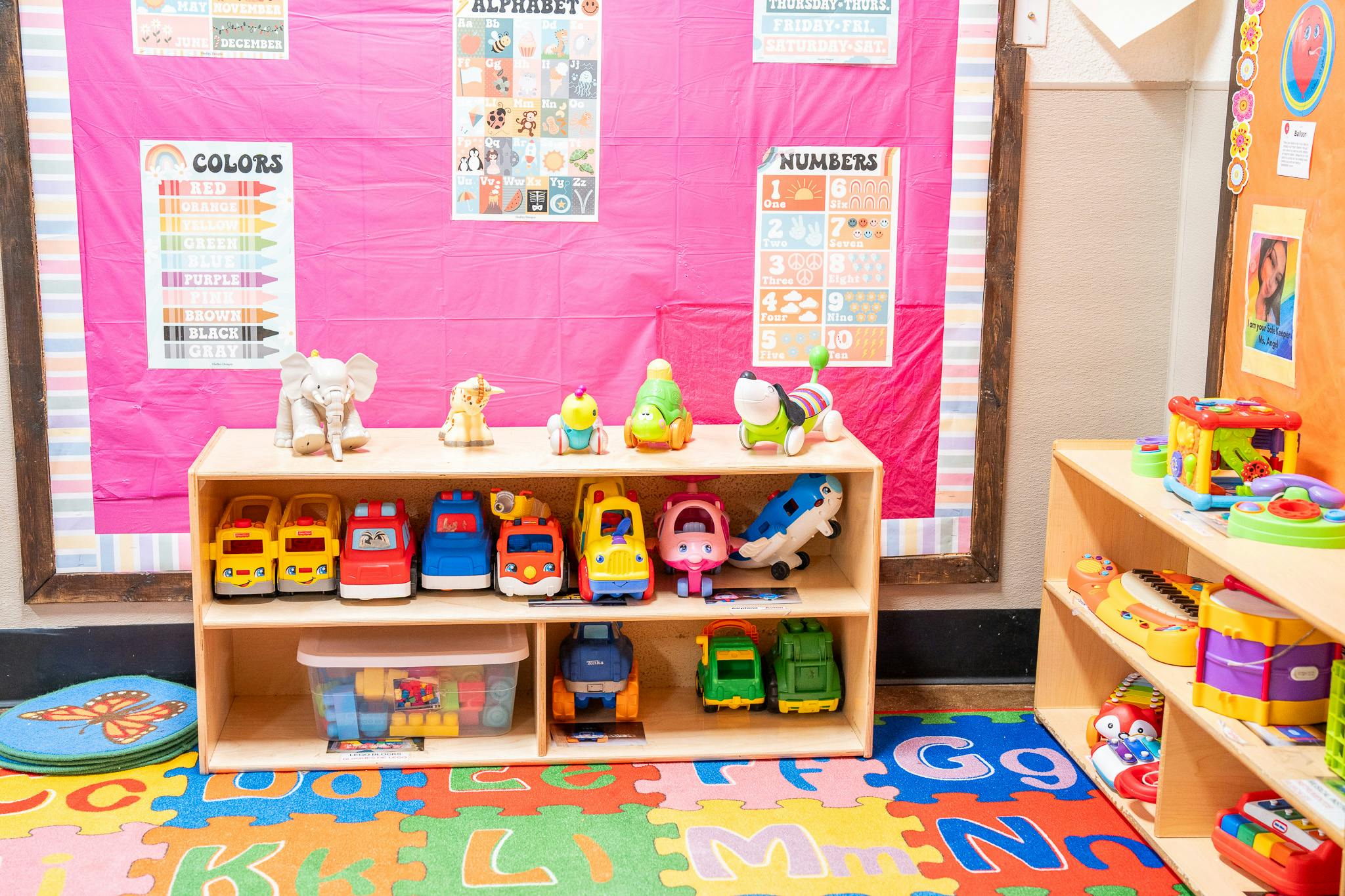 Toy storage shelves in a classroom with educational posters on the wall