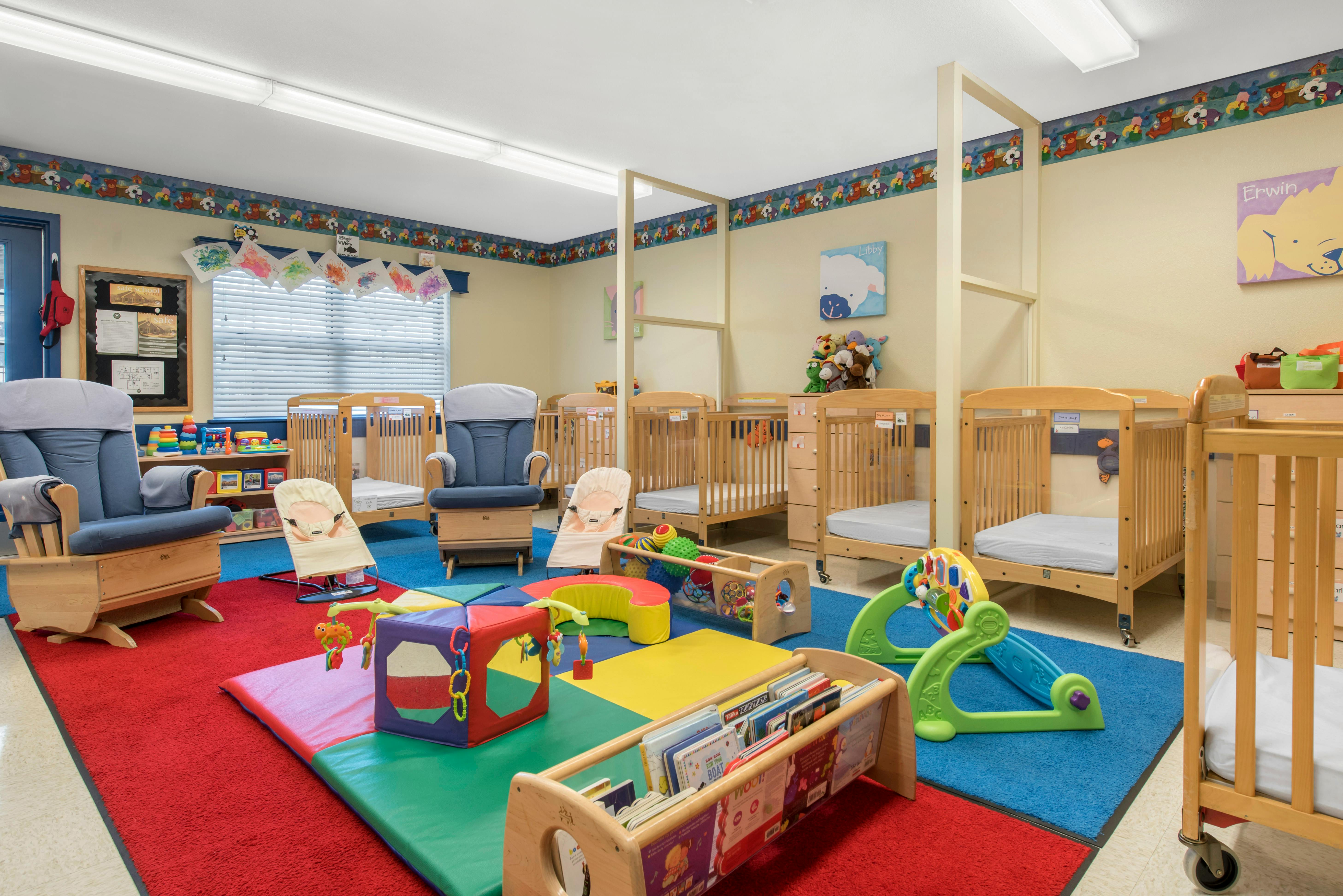 Baby room with multiple cribs, a rocking chair, infant bouncers, and colorful play mats