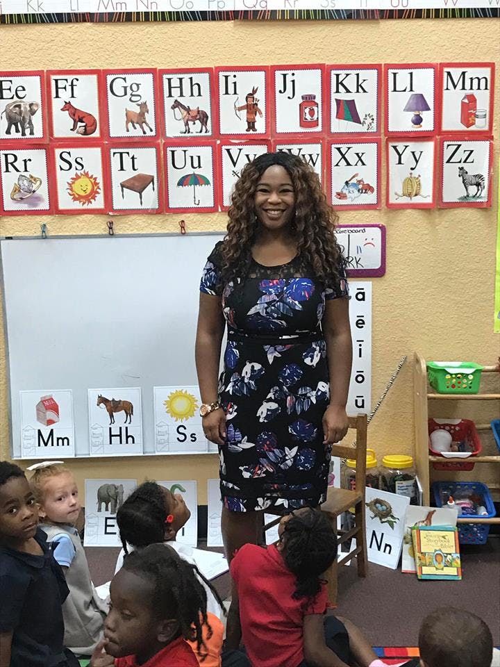 Person standing in front of children in a classroom