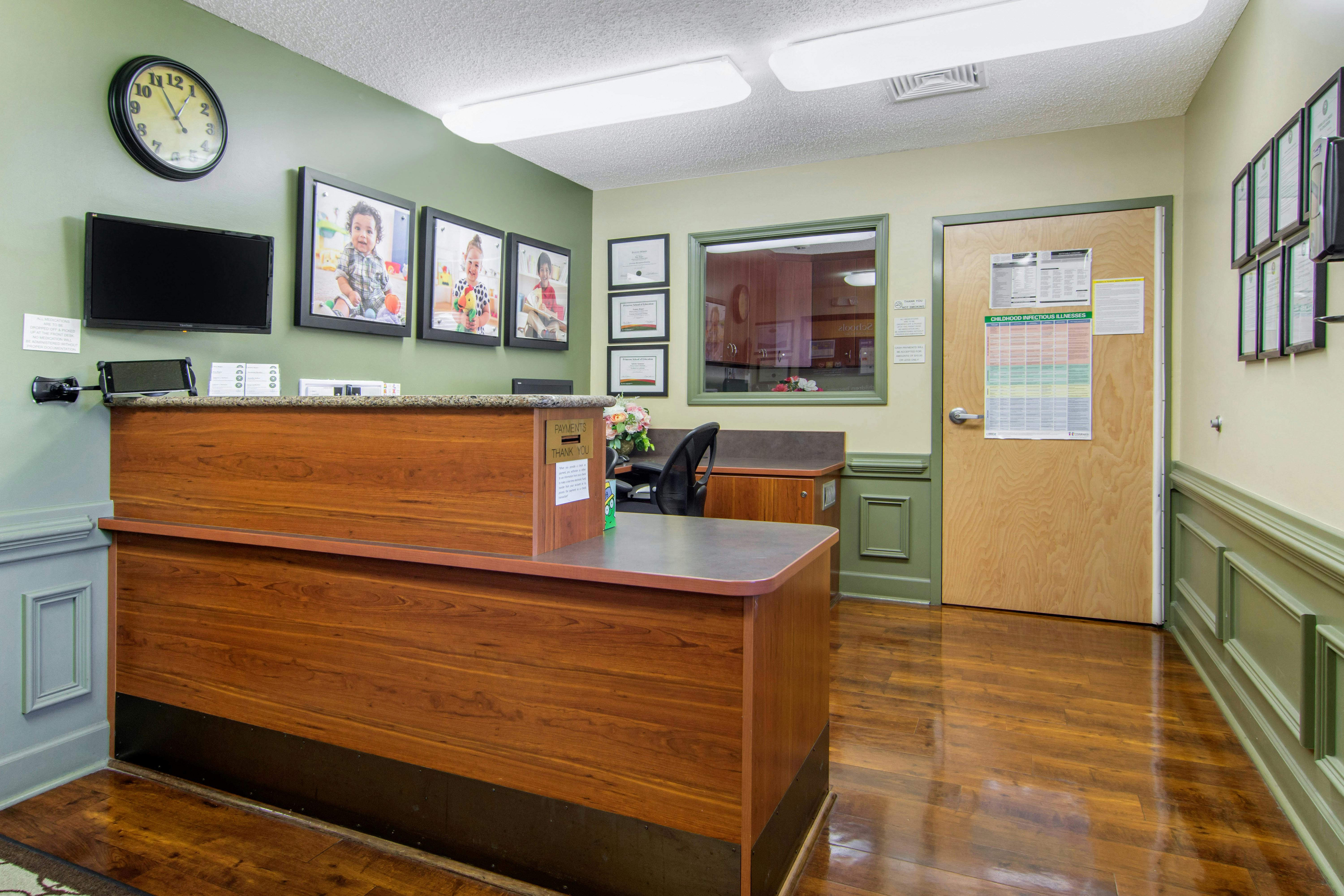 Reception desk with three photos of children on the wall