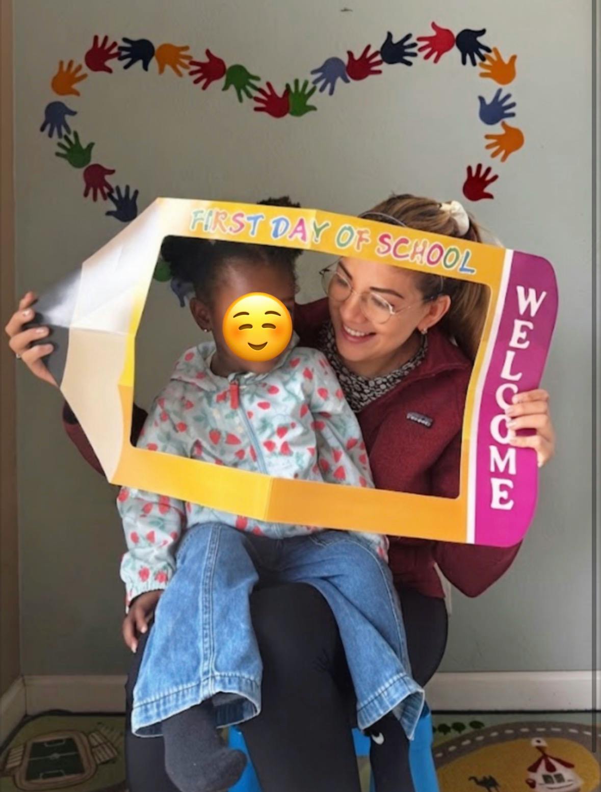 Person holding a First Day of School sign frame around a child