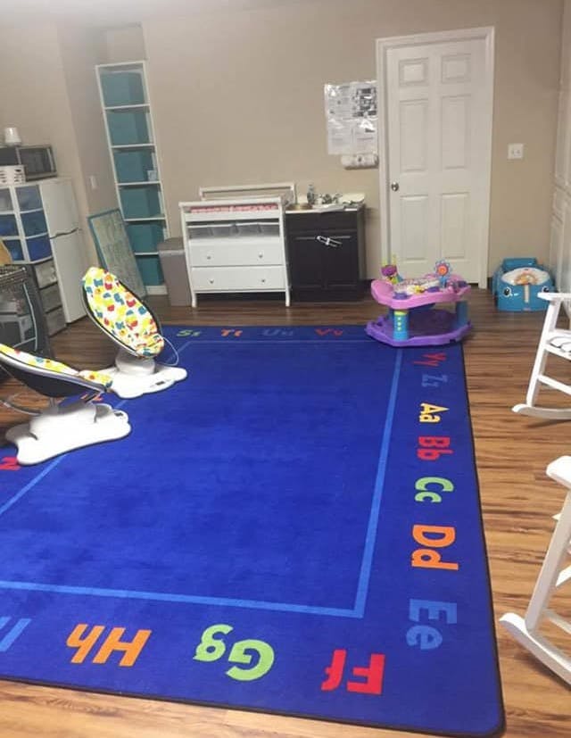 Blue alphabet rug in a room with baby items