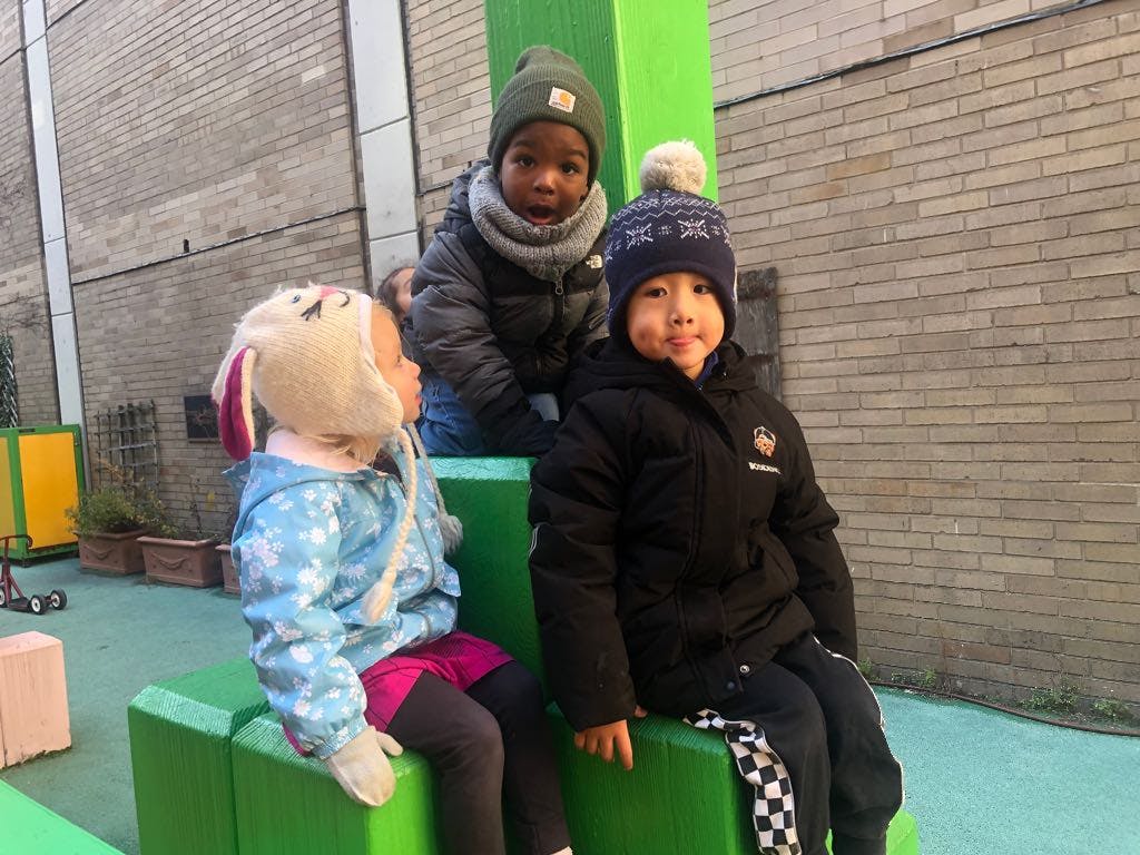 Three children sitting on green play equipment