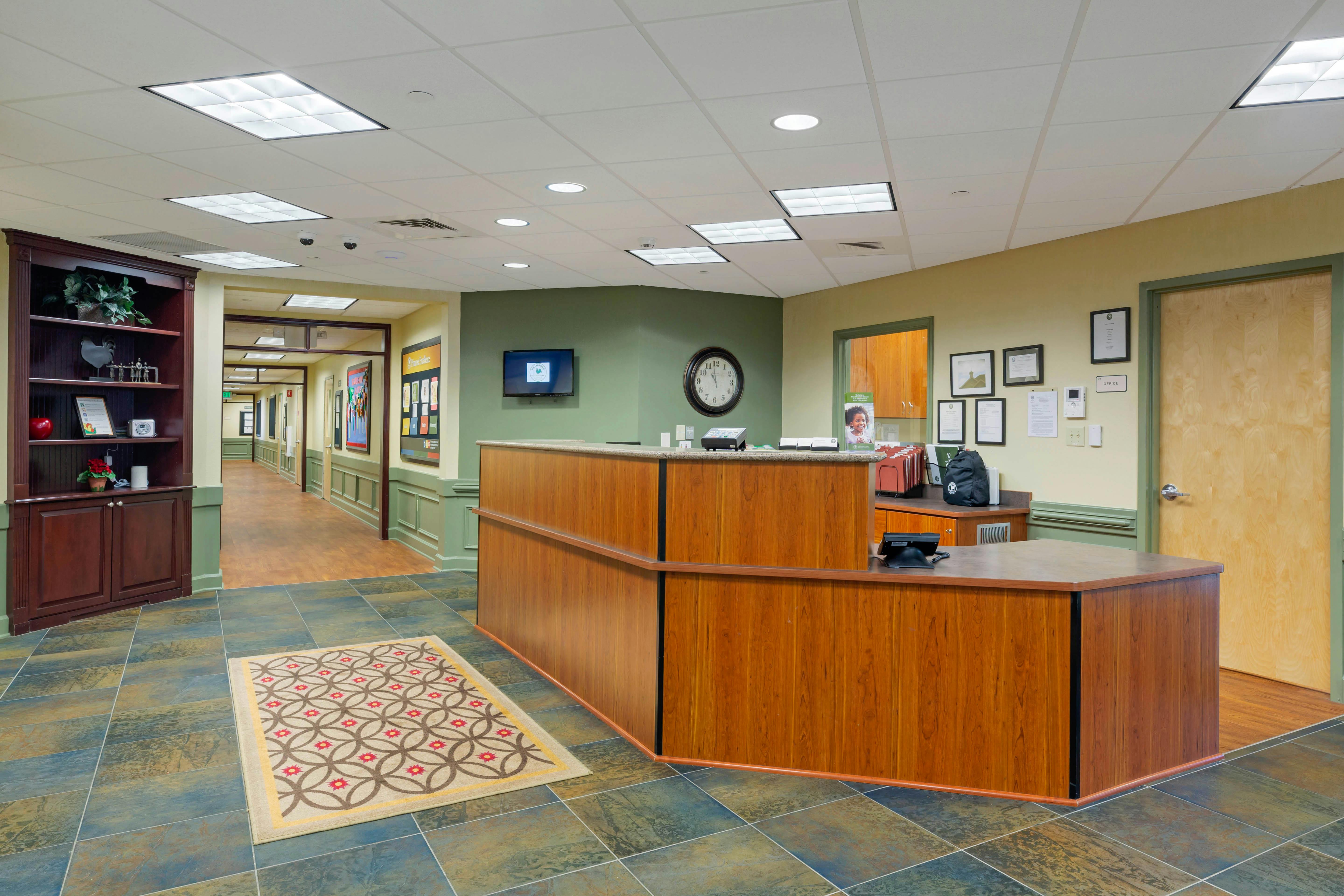 Reception desk in an office building lobby with a hallway and bookshelf