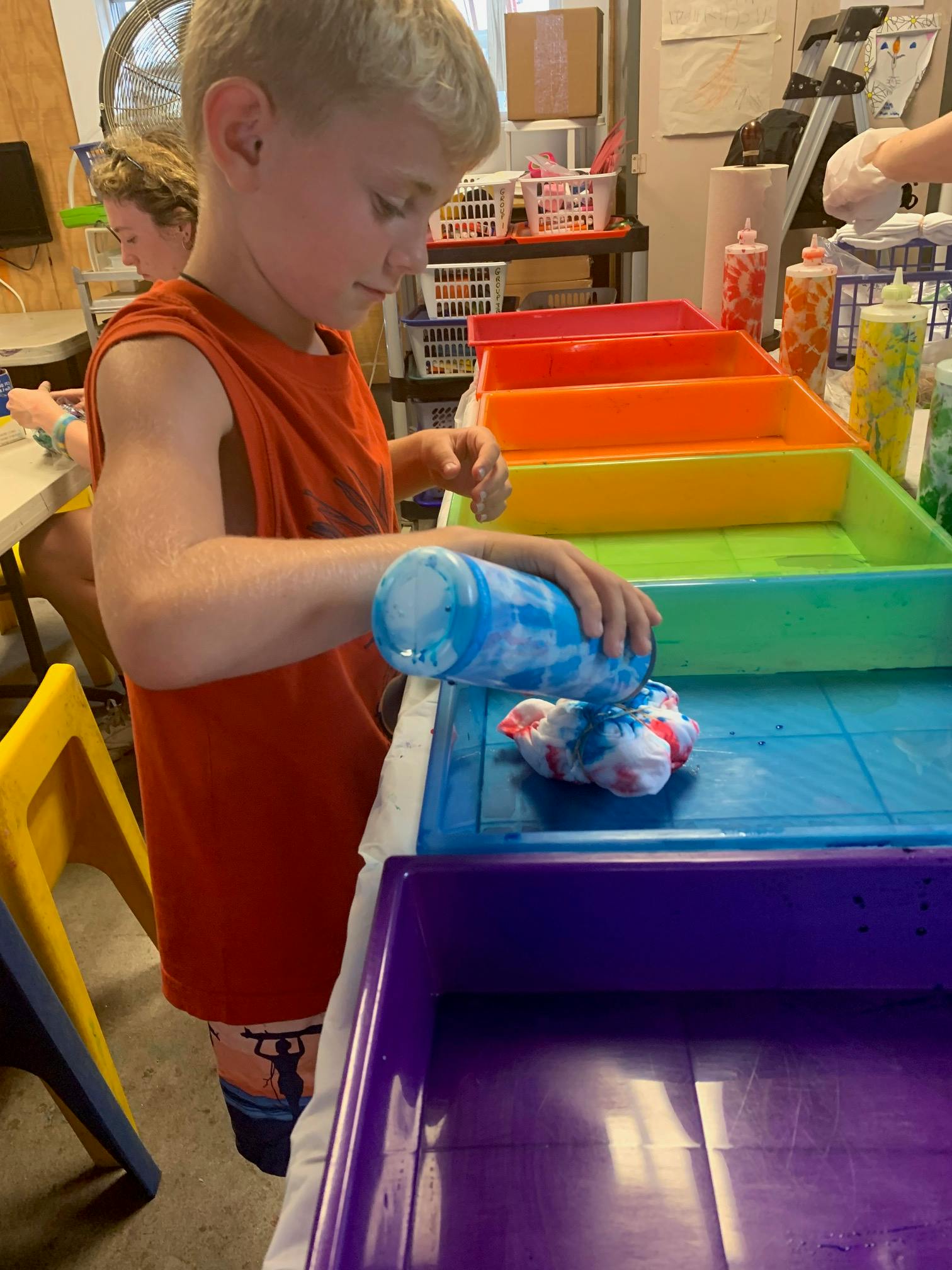 Child tie-dyeing a shirt with blue dye
