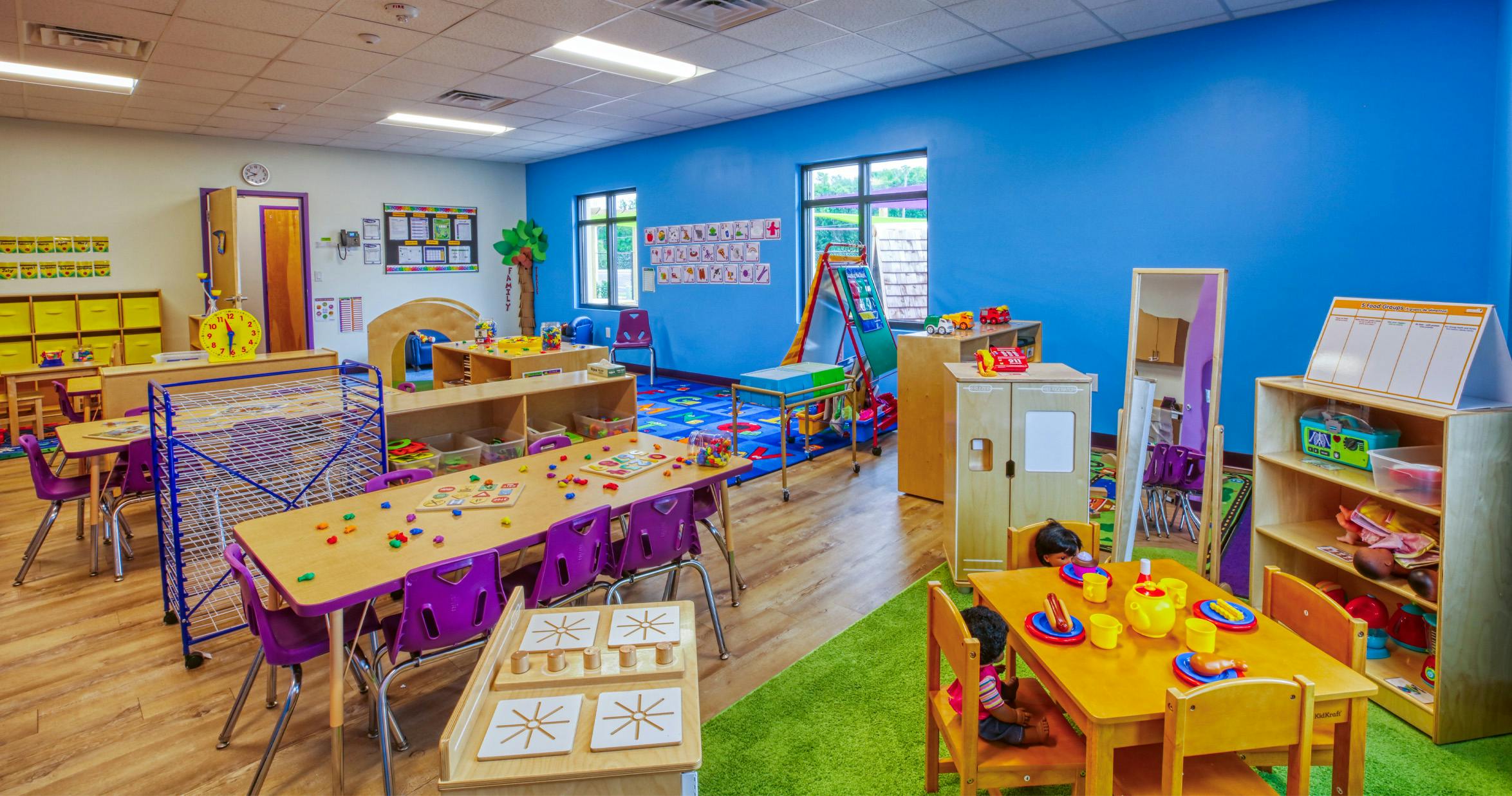 Children's classroom with blue and white walls, tables, chairs, and play areas