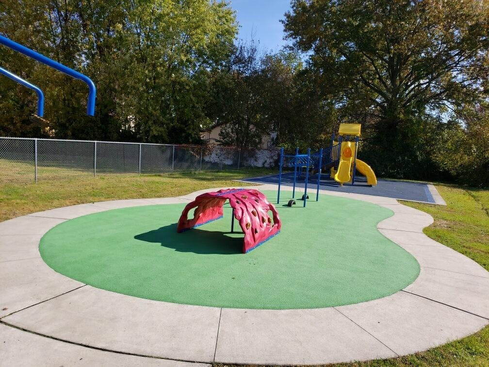 Playground with red climbing tunnel, blue monkey bars, and yellow slide