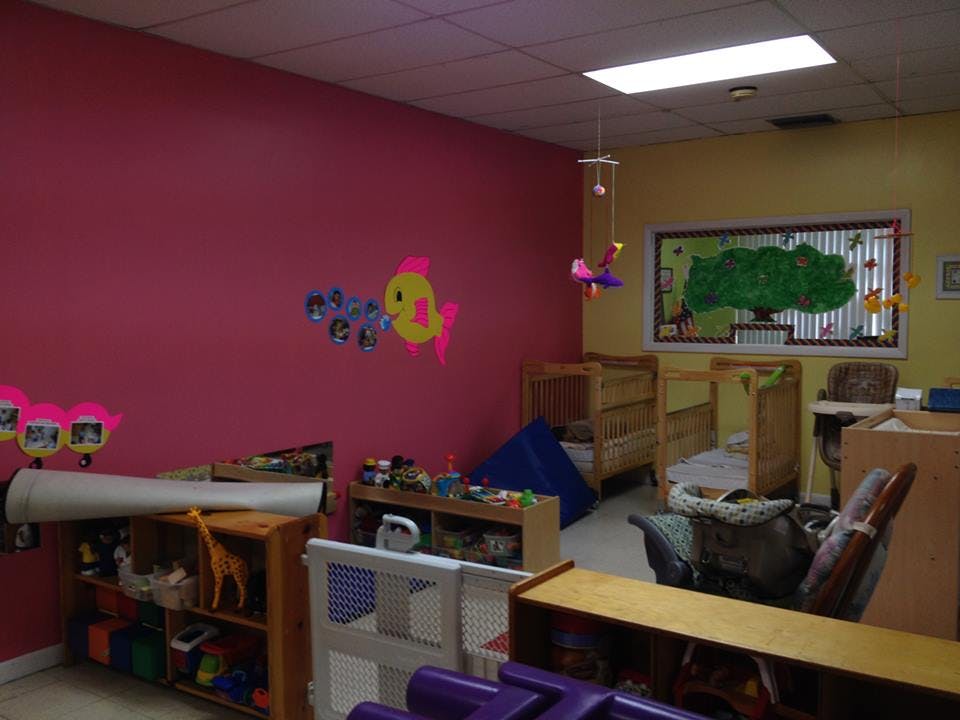 Playroom with pink and yellow walls, cribs, and toys