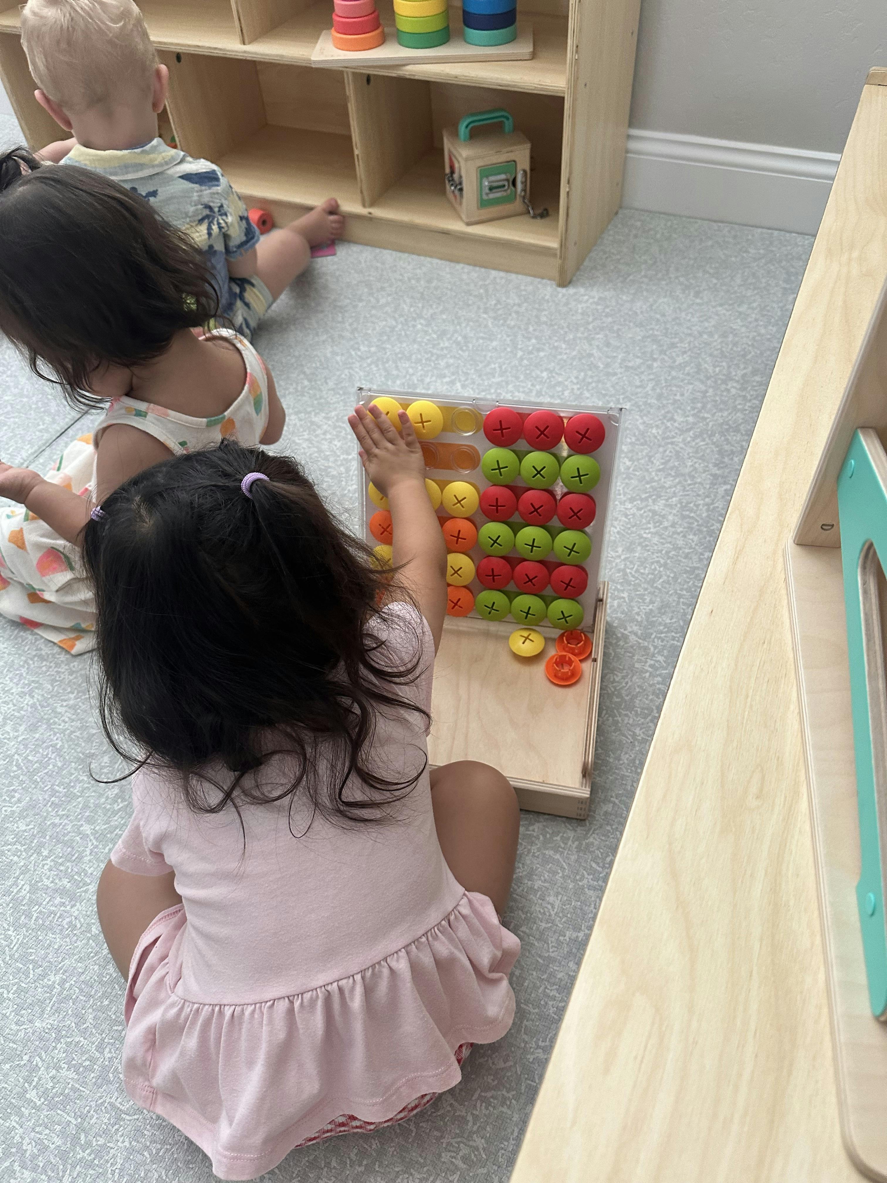 Three children playing with a board game and toys on the floor