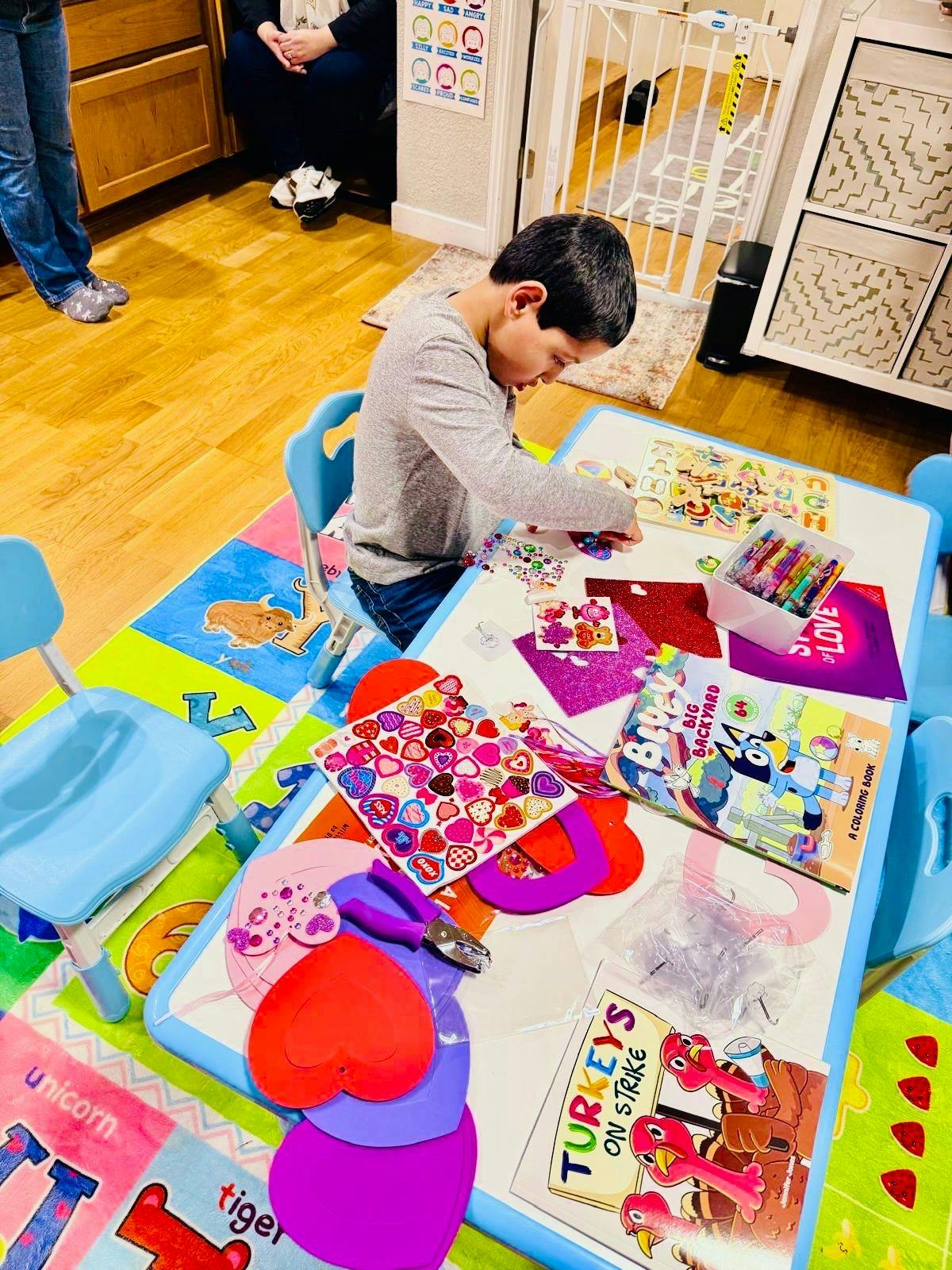 Child crafting with stickers and paper hearts at a small table