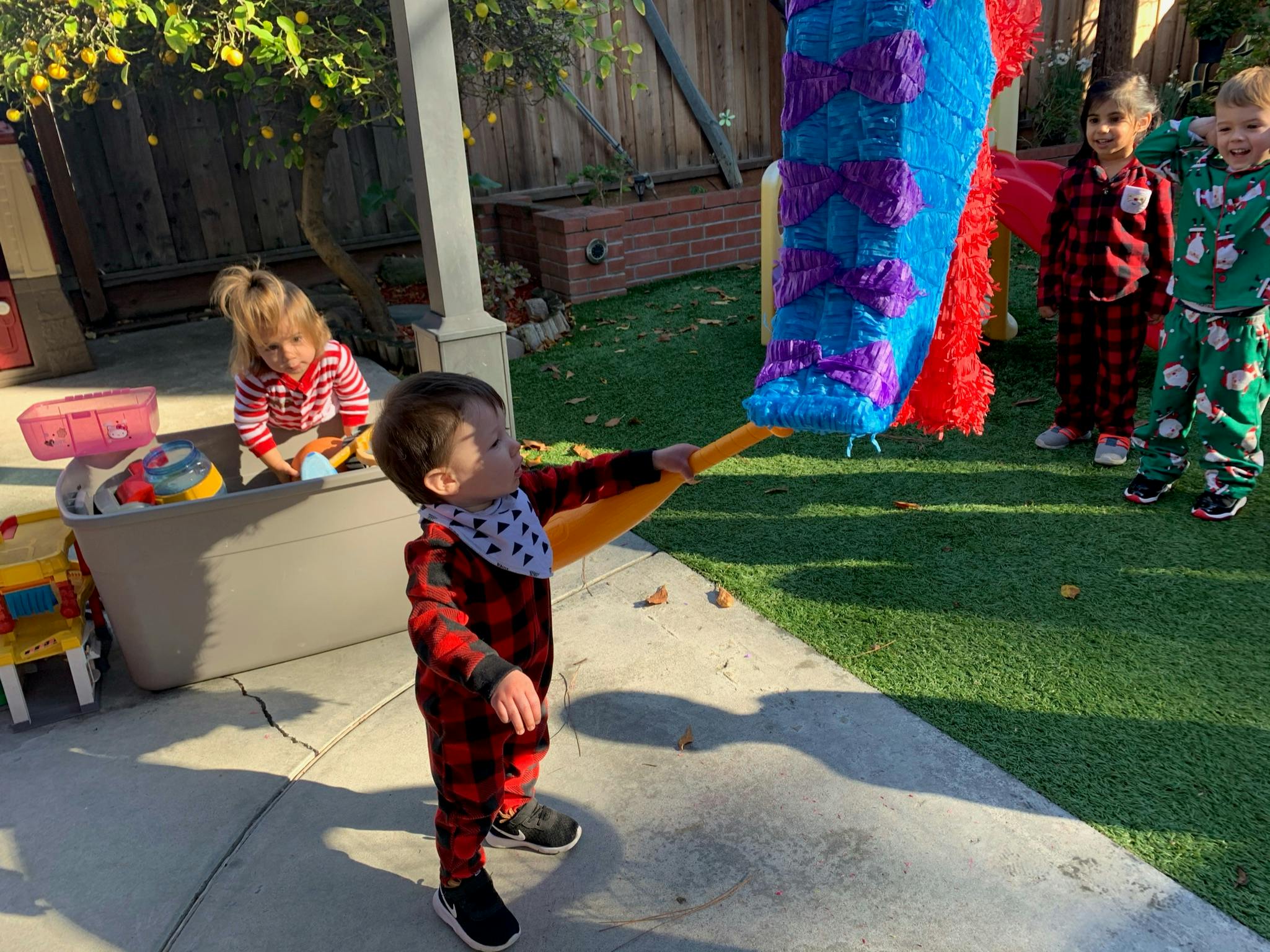 Child hitting a piñata with a stick while other children watch