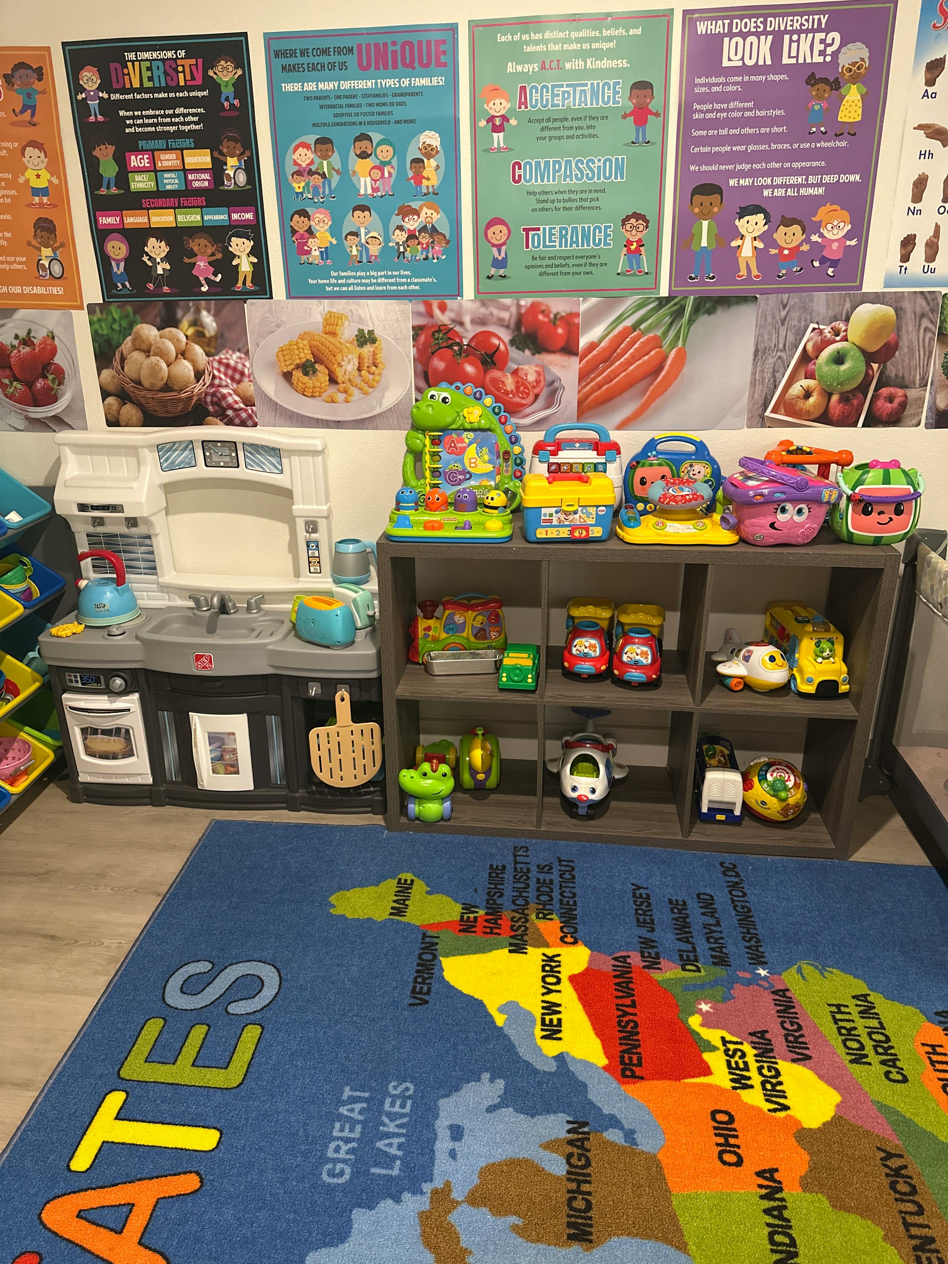 Classroom or playroom with a US map rug, educational posters on diversity, toys, and play kitchen