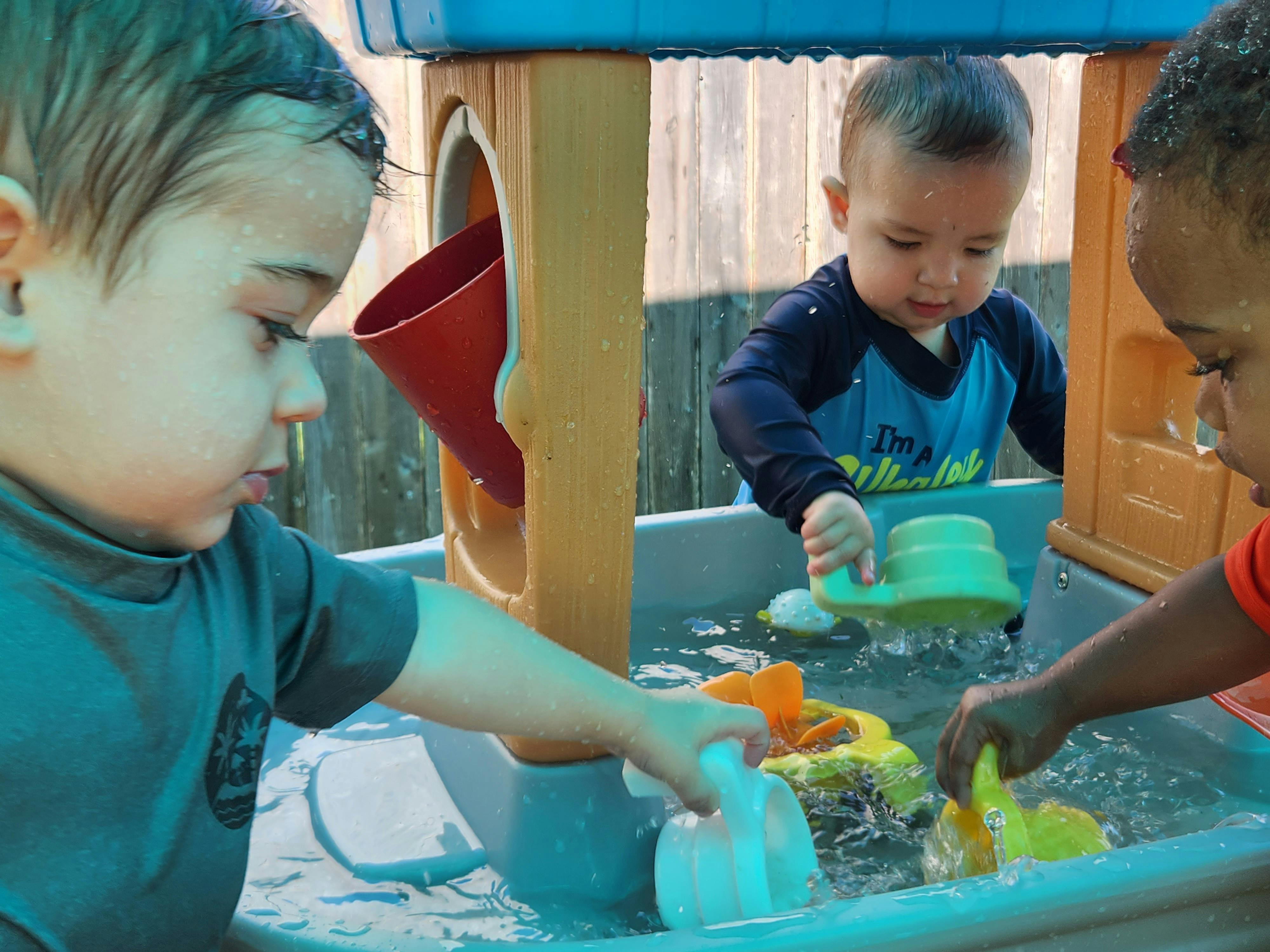 Three children playing together at a water table