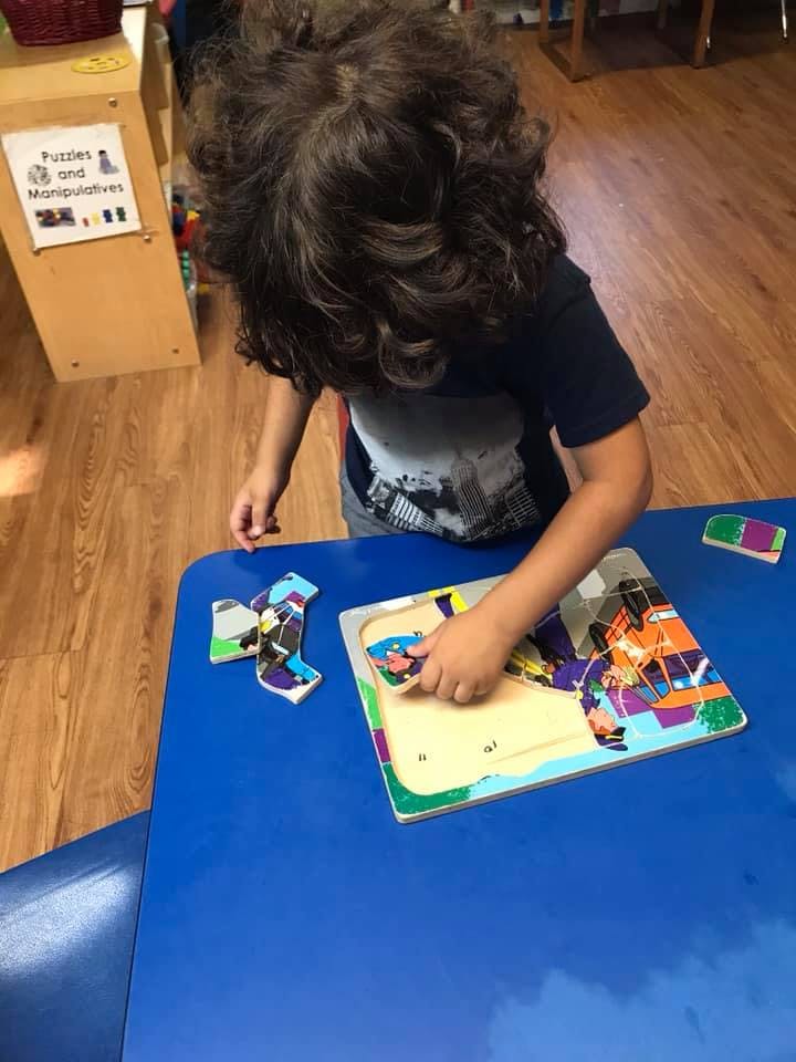 Child playing with a puzzle on a blue table
