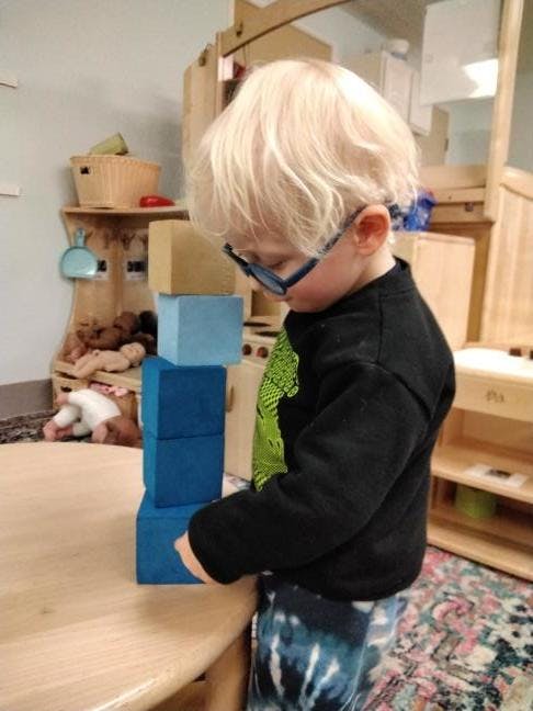 Child in glasses stacking blue blocks on a table