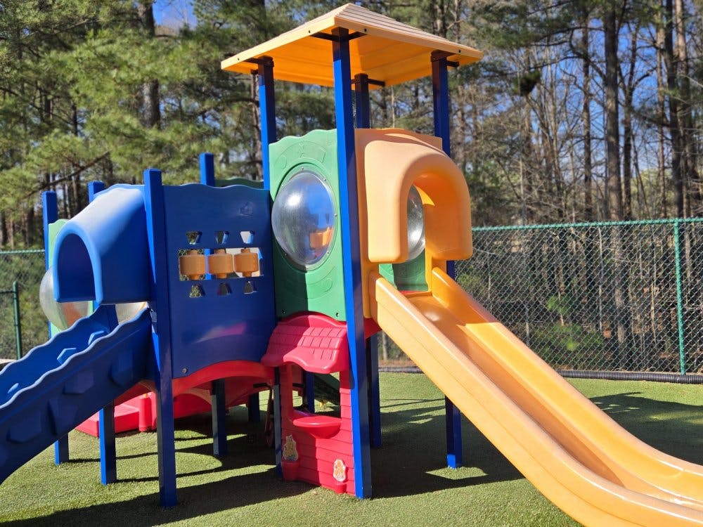 Playground structure with multiple slides and climbing areas on artificial grass