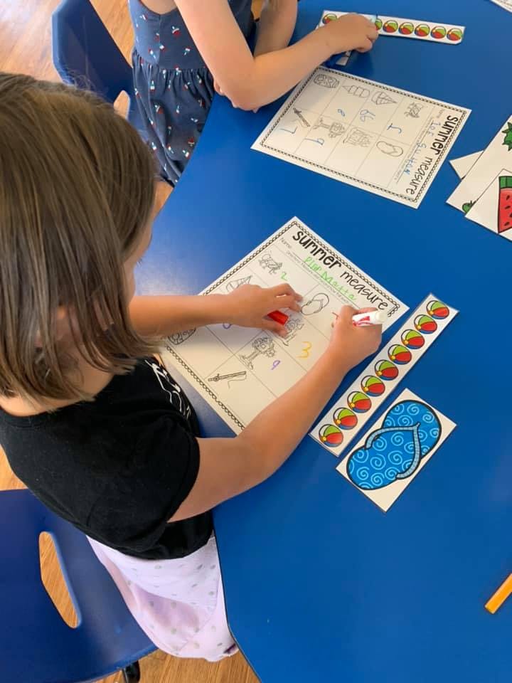 Child writing on a worksheet at a blue table