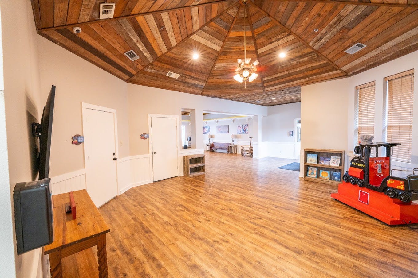 Spacious room with wood-paneled ceiling, toy train ride, and bookshelves