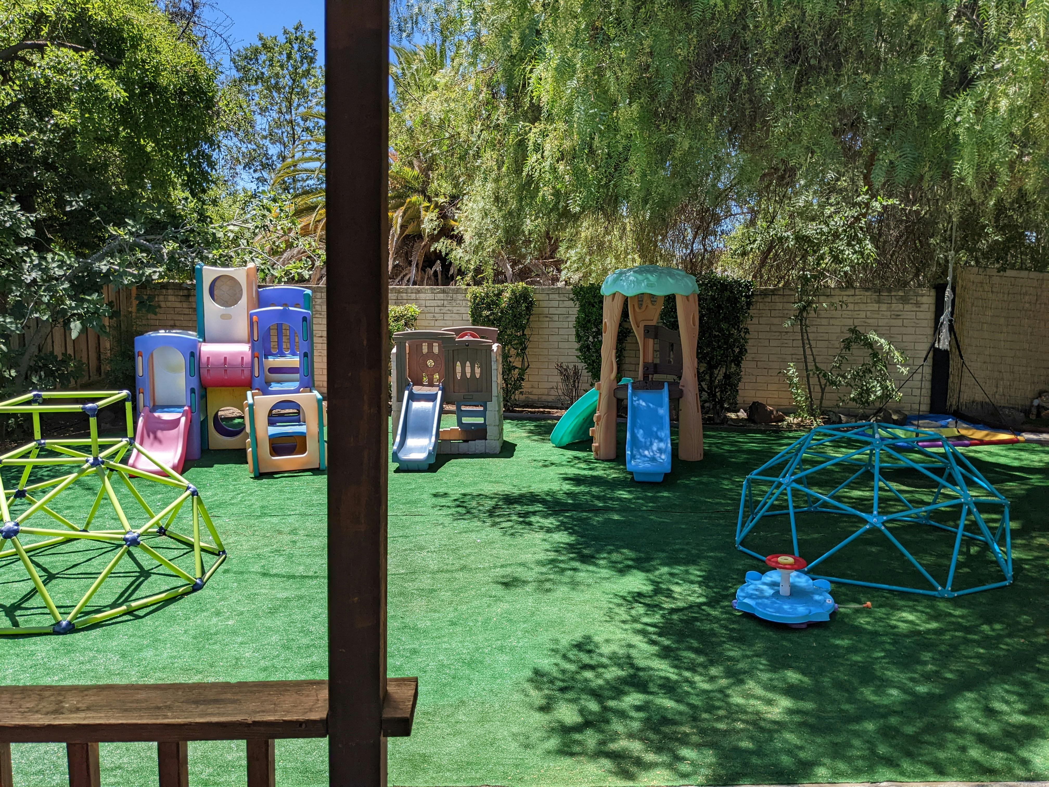 Outdoor playground with multiple slides, climbing structures, and artificial turf