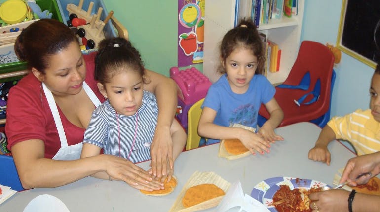Adult and children making food at a table