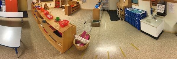Empty classroom with tables, shelves, and a sink