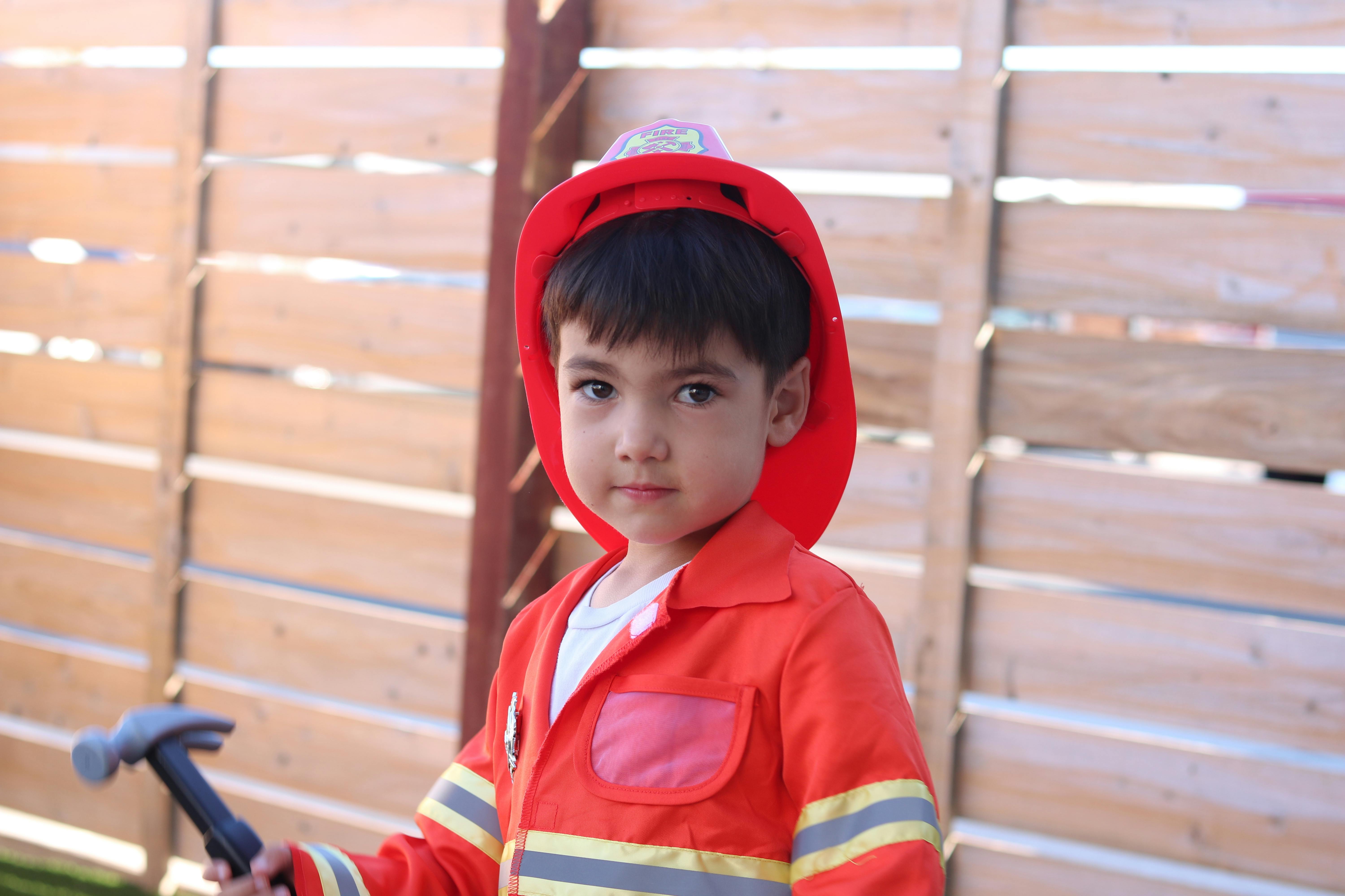 Child wearing a toy firefighter costume and holding a toy hammer