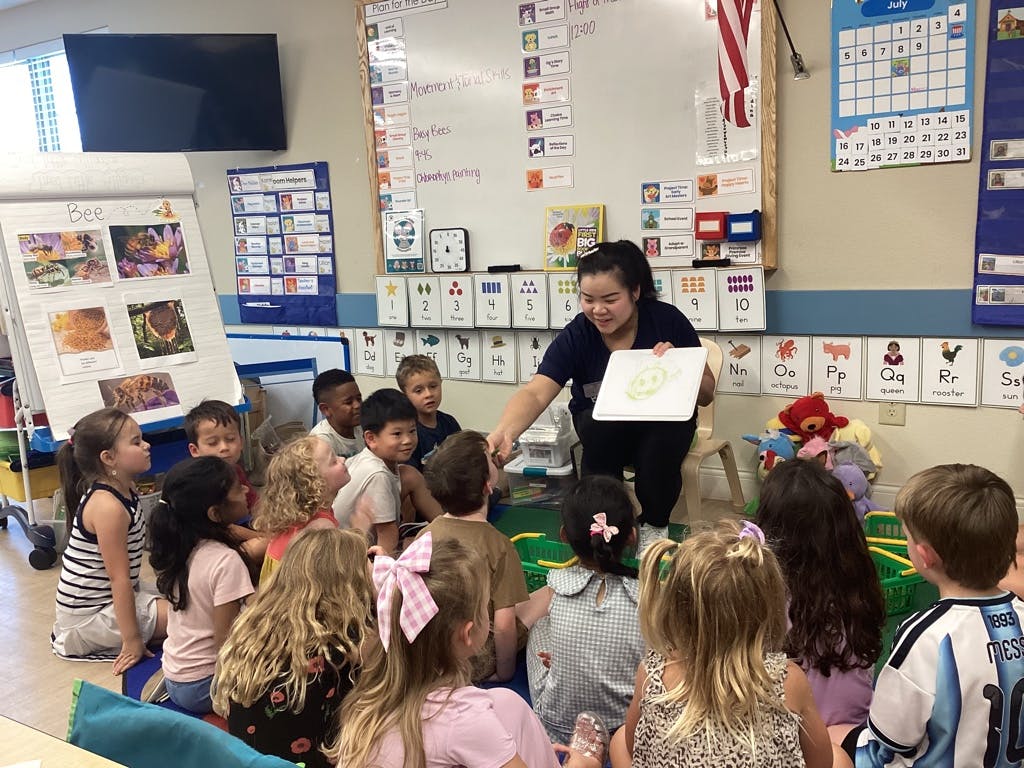 Teacher holding a sign while interacting with children in a classroom