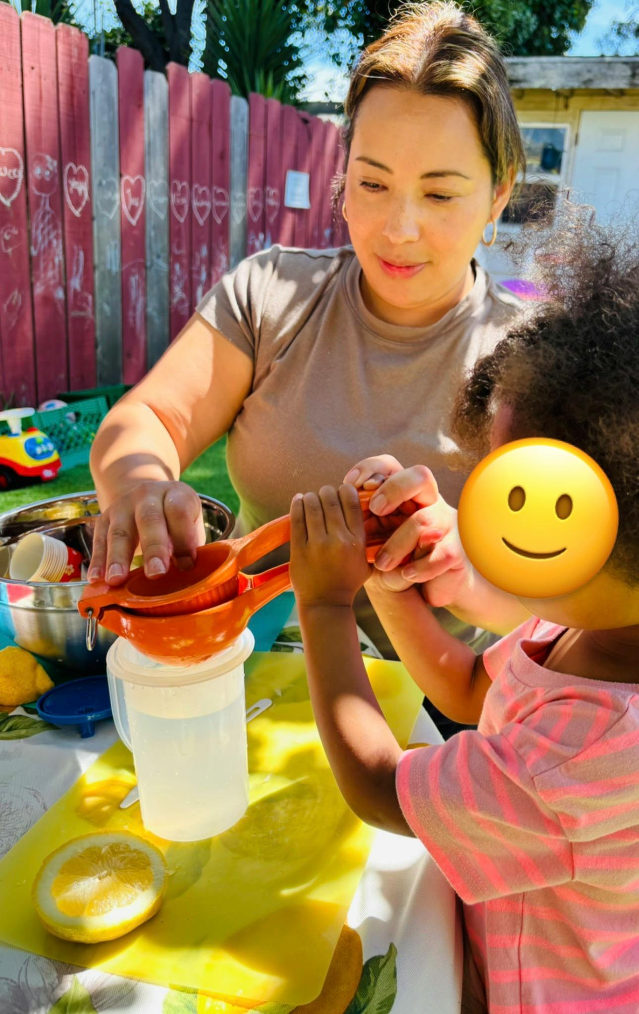Adult and child using a manual citrus juicer to squeeze lemon juice into a pitcher