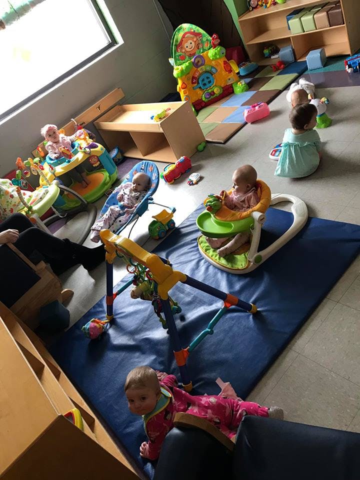 Multiple babies in various play equipment in a room