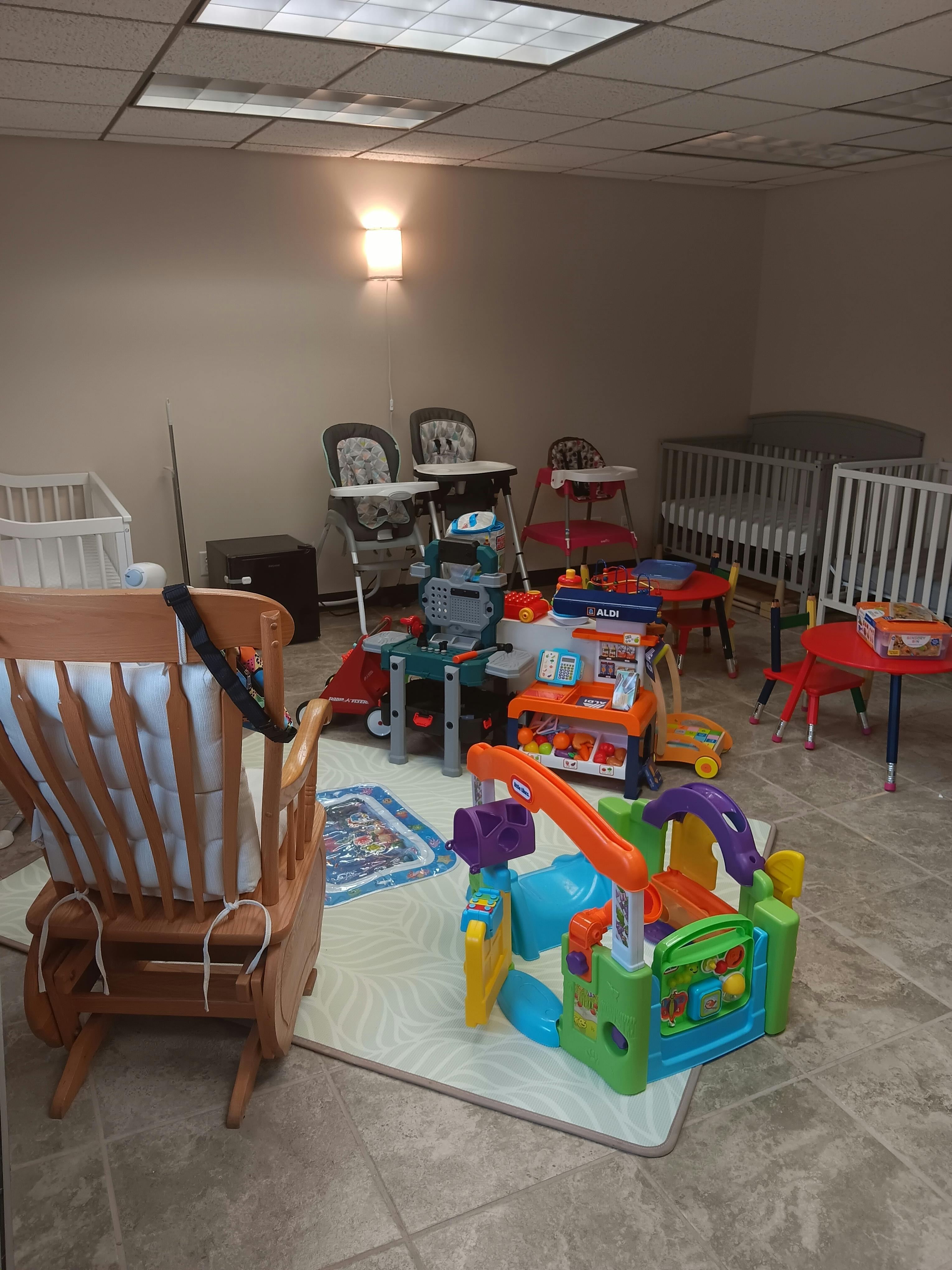 Room with cribs, high chairs, and various children's toys