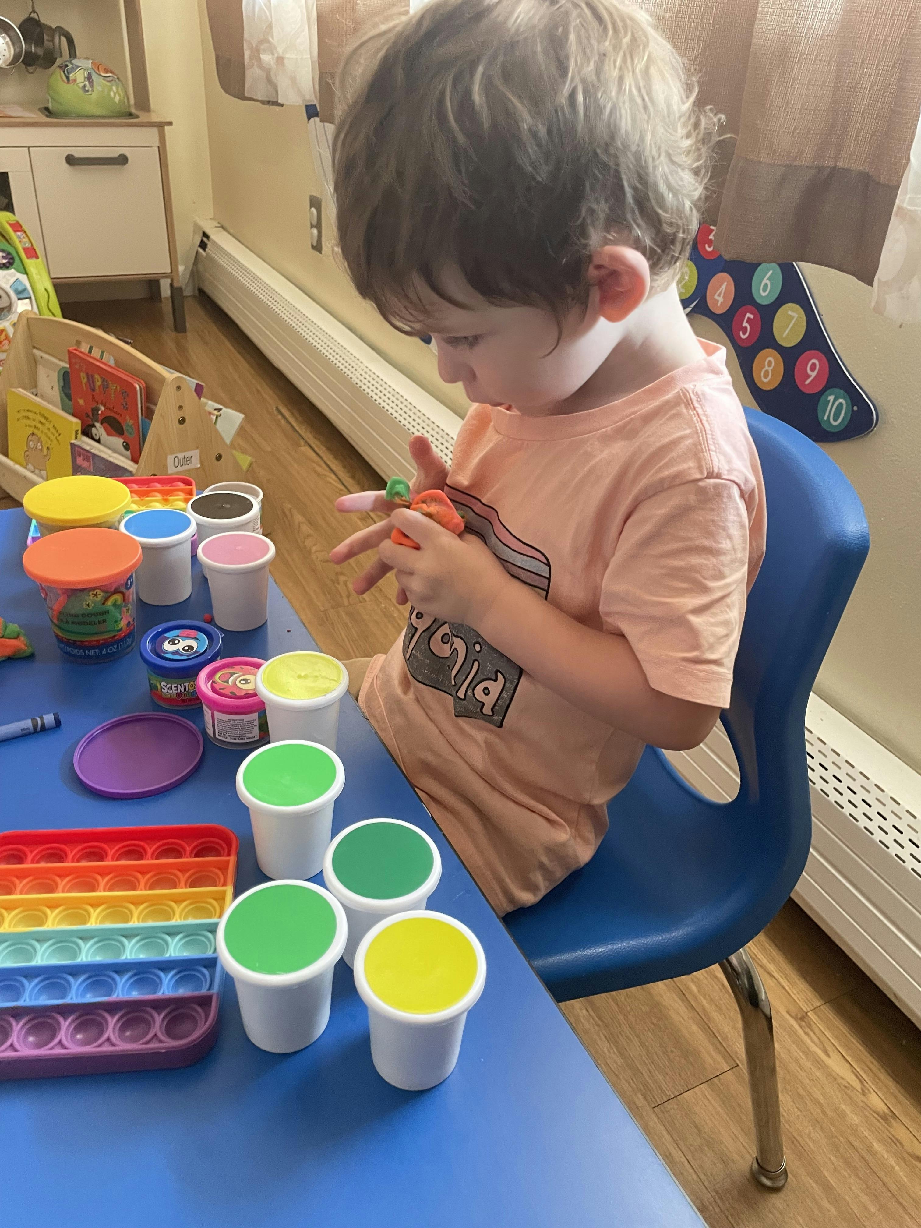 Child sitting at a desk playing with modeling clay
