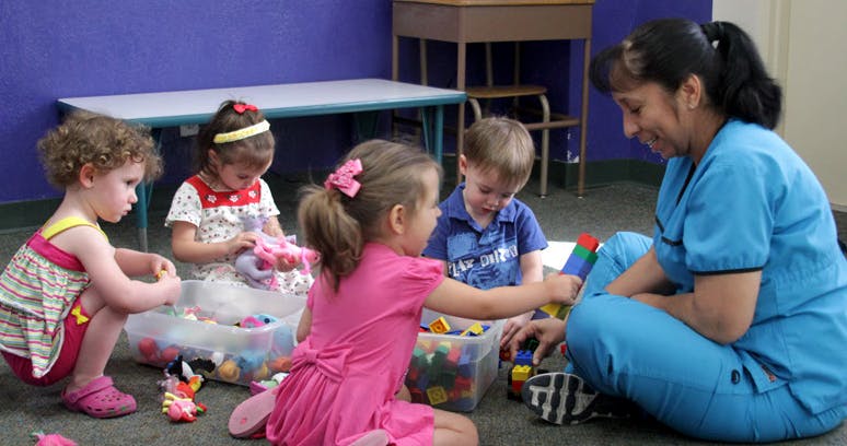 Adult and children playing with toys on the floor