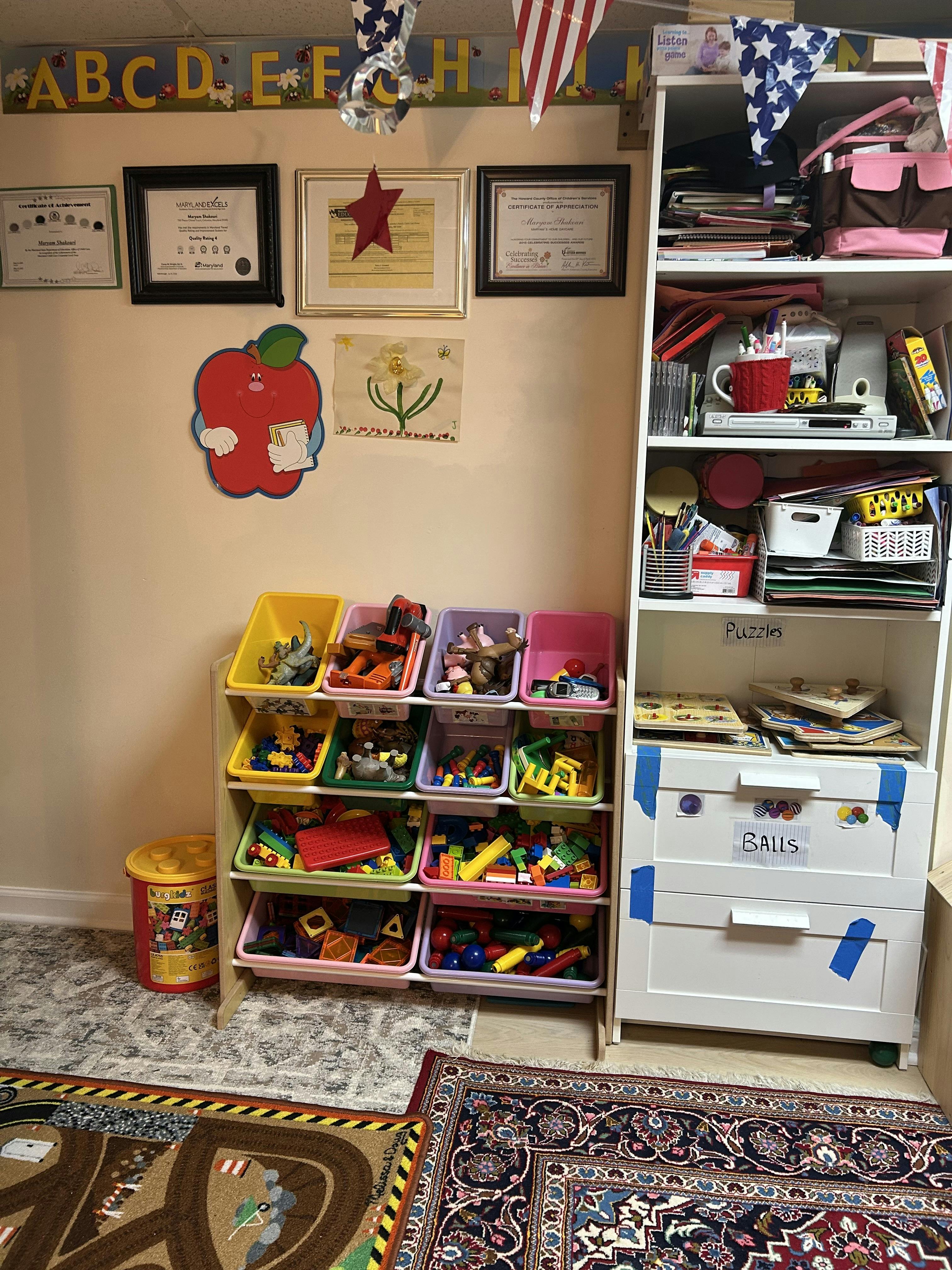 Toy storage bins filled with various toys next to a white bookshelf