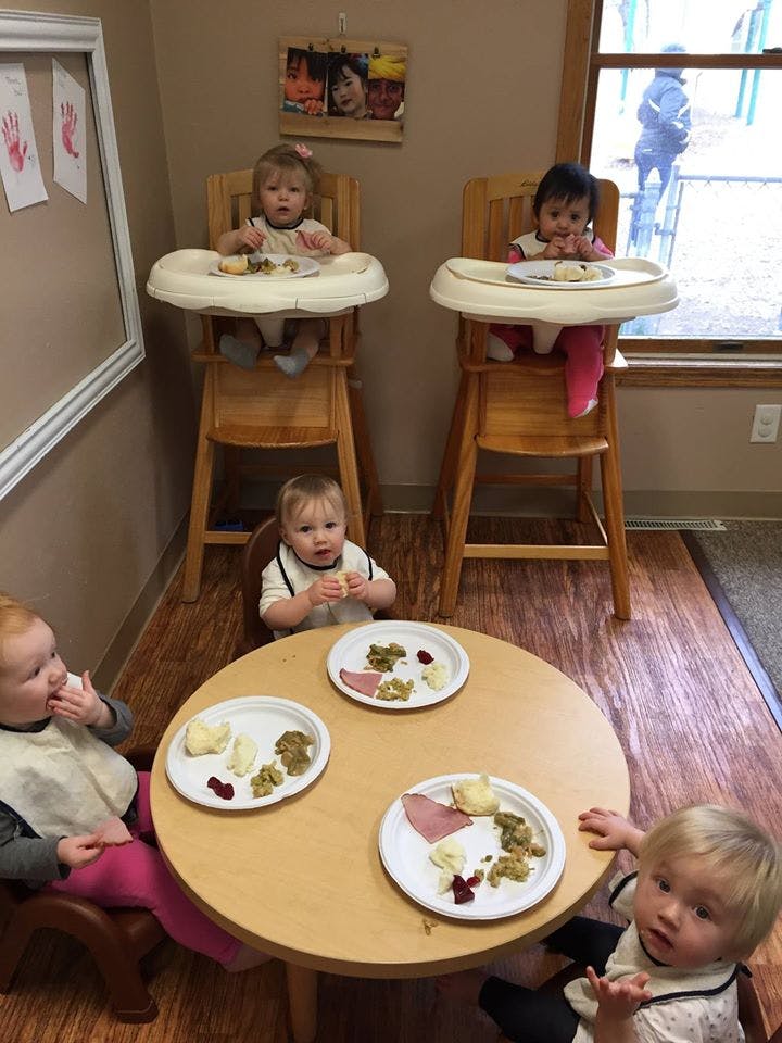 Four children eating at a table and in high chairs