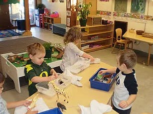 Three children playing with toys at a table in a classroom