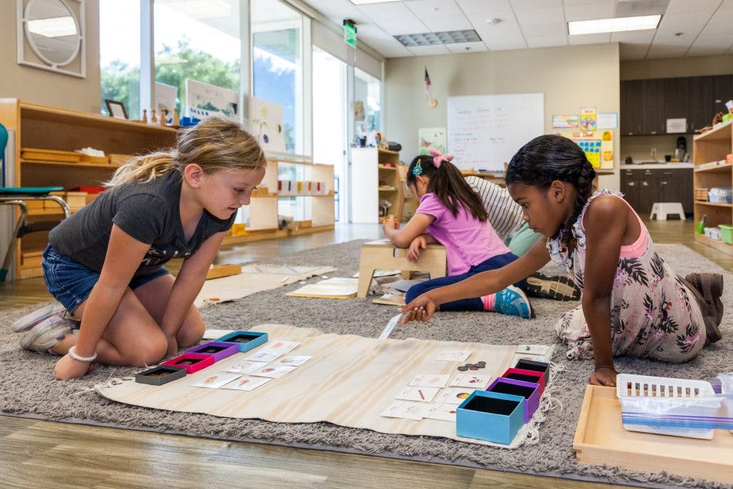 Three children working on a rug in a classroom
