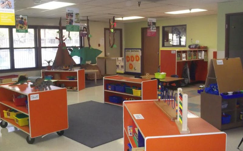 Classroom with toy dinosaur cutouts and orange shelves filled with toys