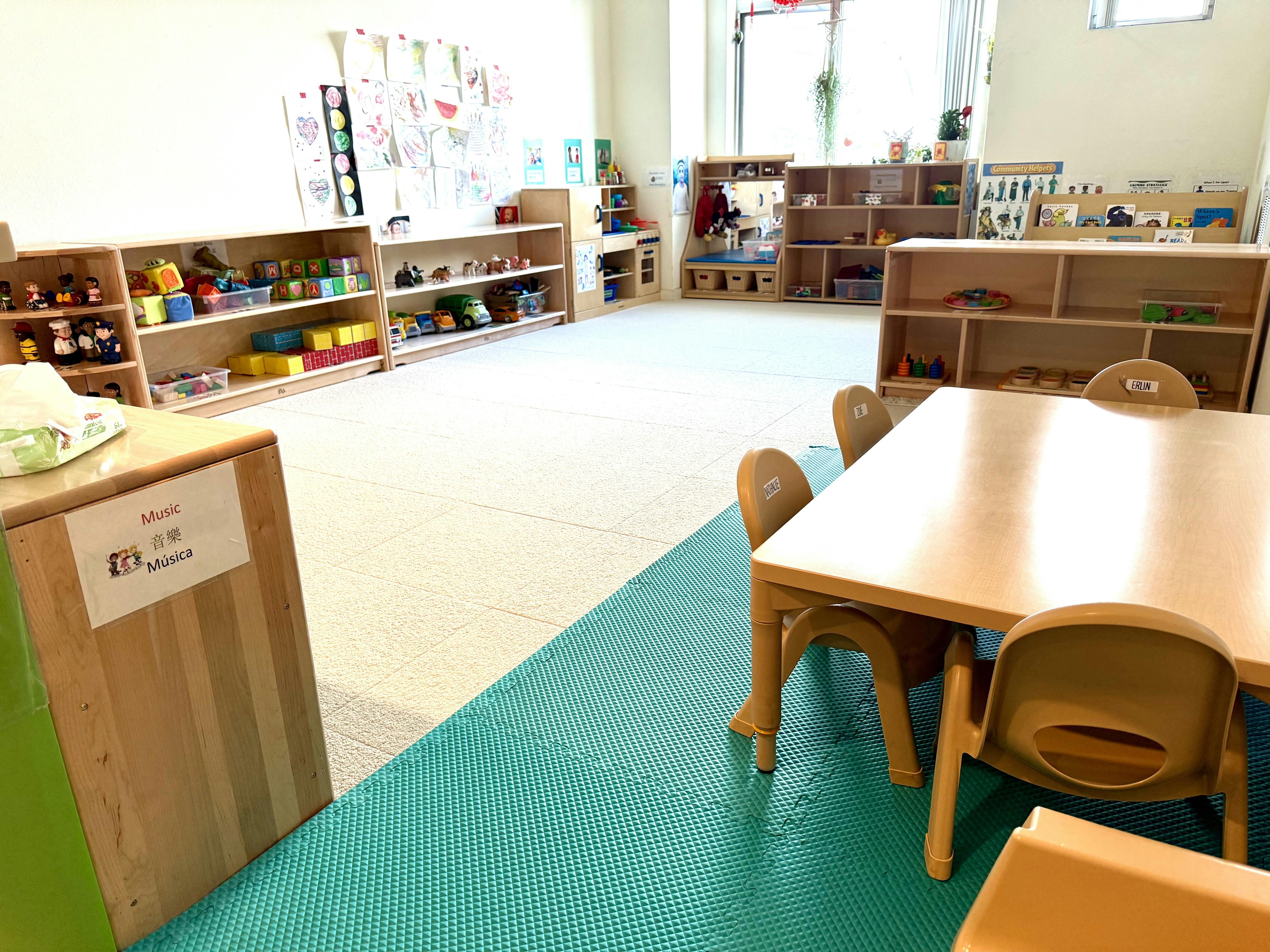Empty preschool classroom with toy storage shelves and a small table with chairs