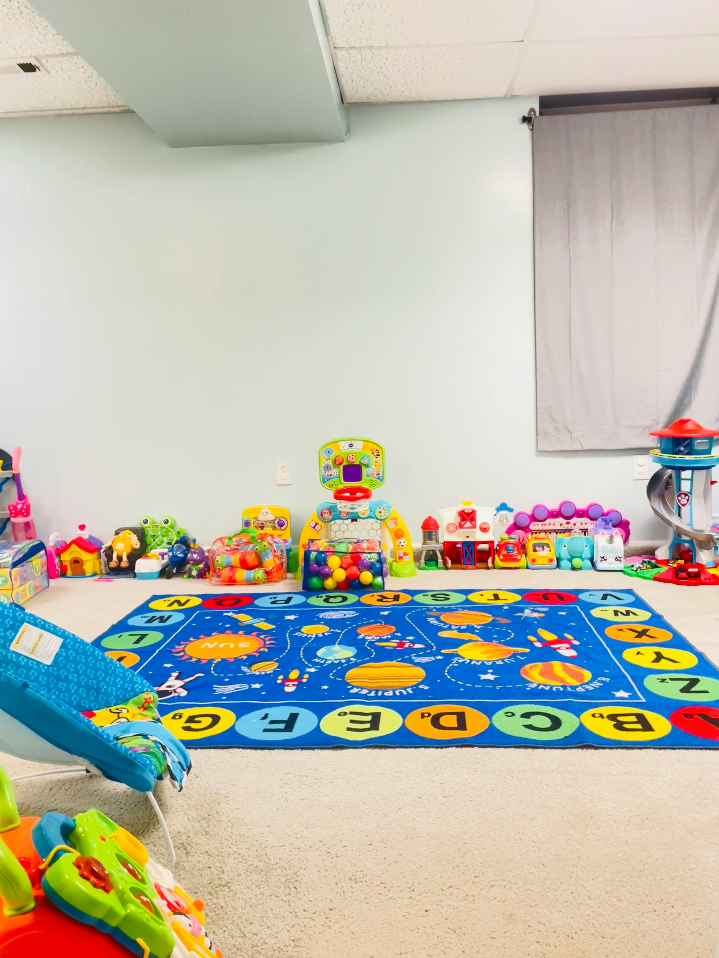 Playroom with a blue alphabet rug and various toys
