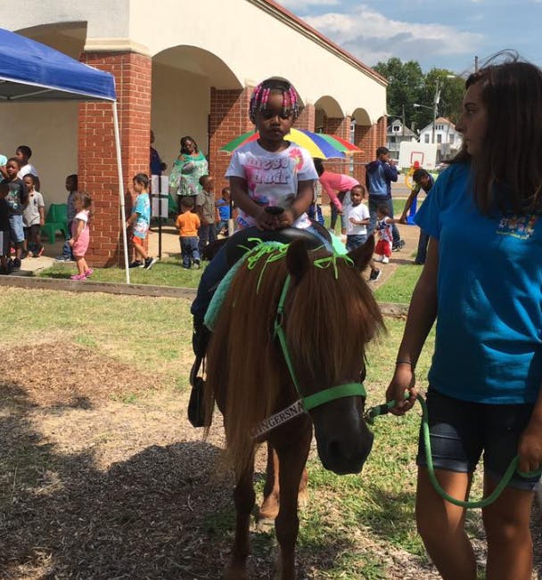 Child riding a pony led by a person