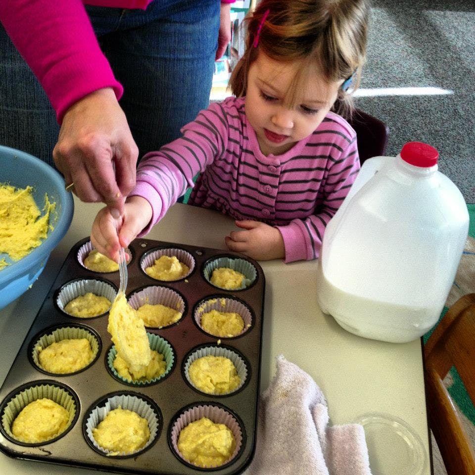 Adult and child filling a muffin tin with batter
