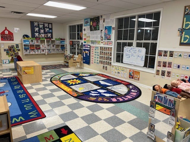 A classroom with alphabet rugs, learning materials on walls, and play items