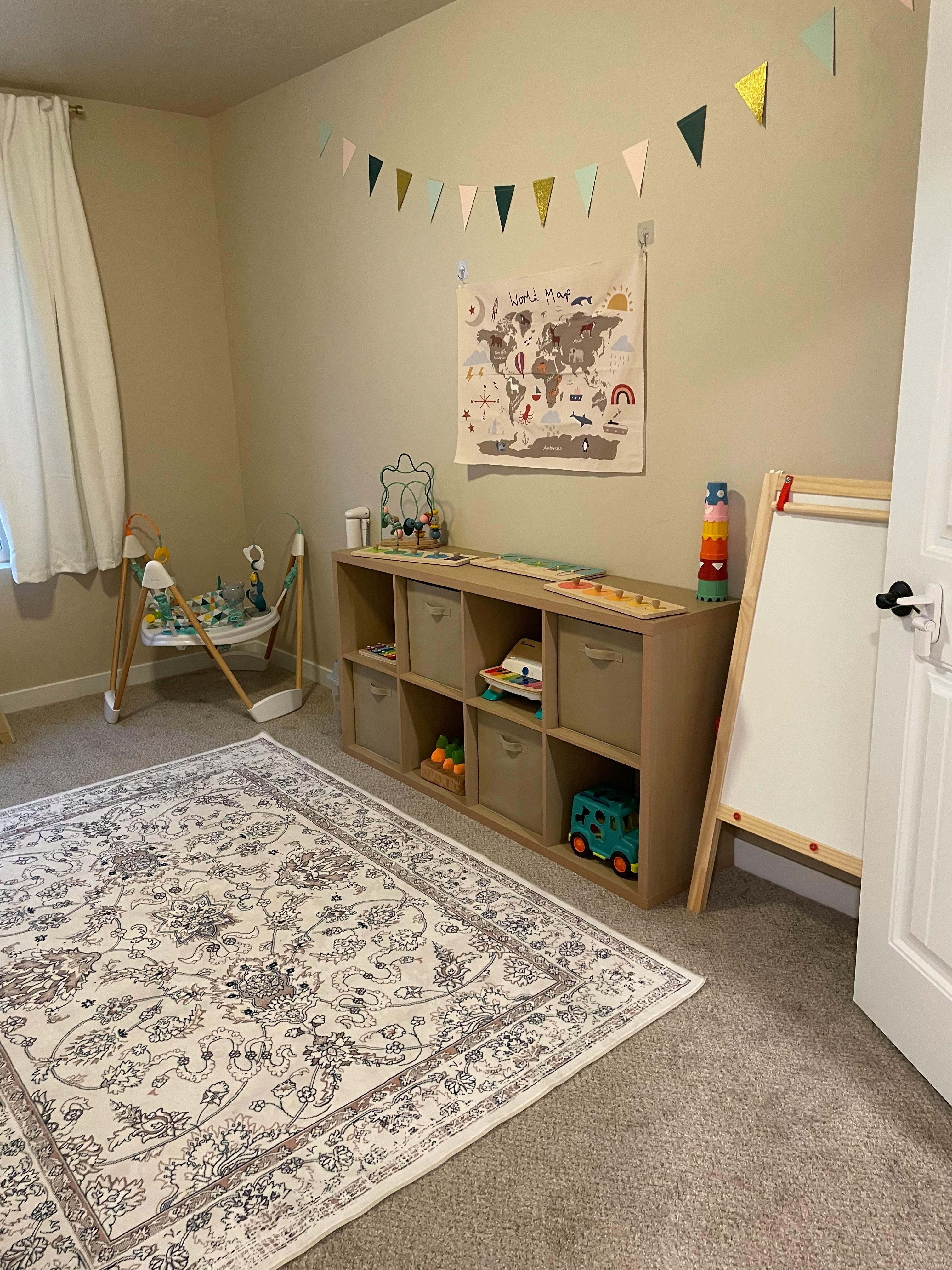 Child's room with a rug, toy shelf, easel, and baby bouncer