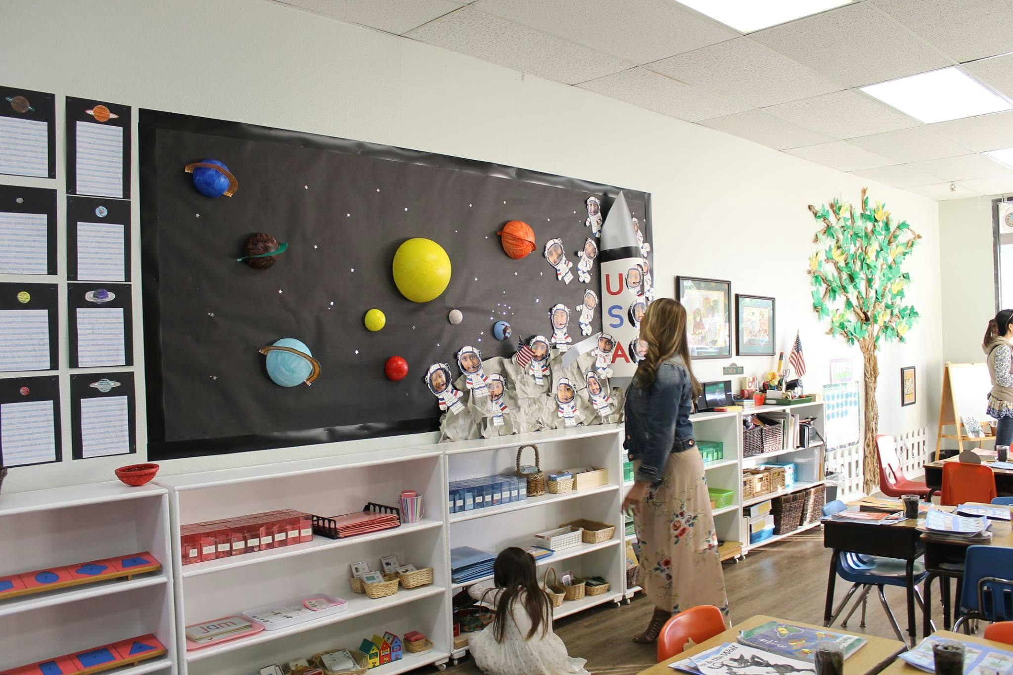 Classroom with a solar system display on a wall and a person standing