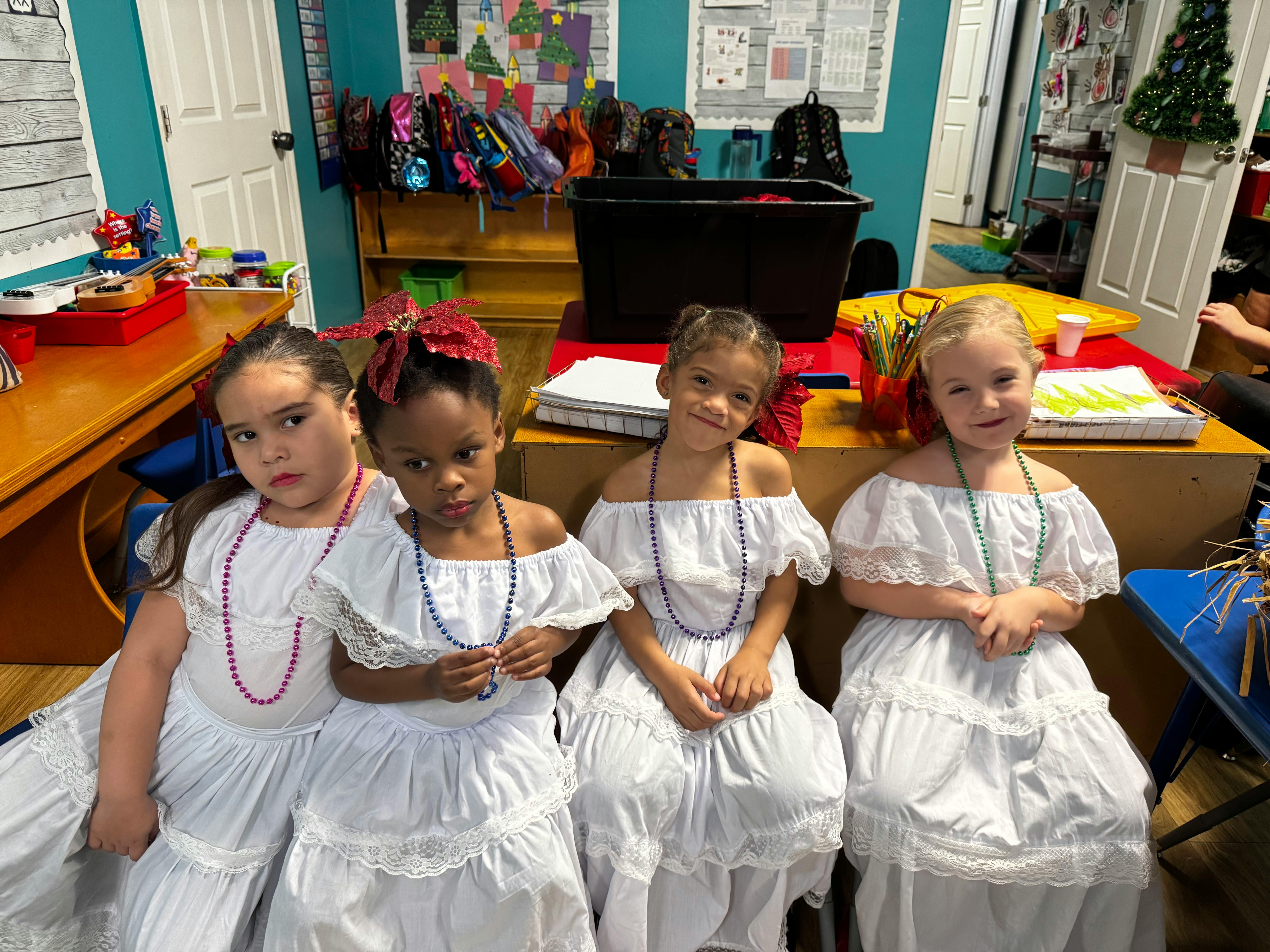 Four children in white dresses and beaded necklaces