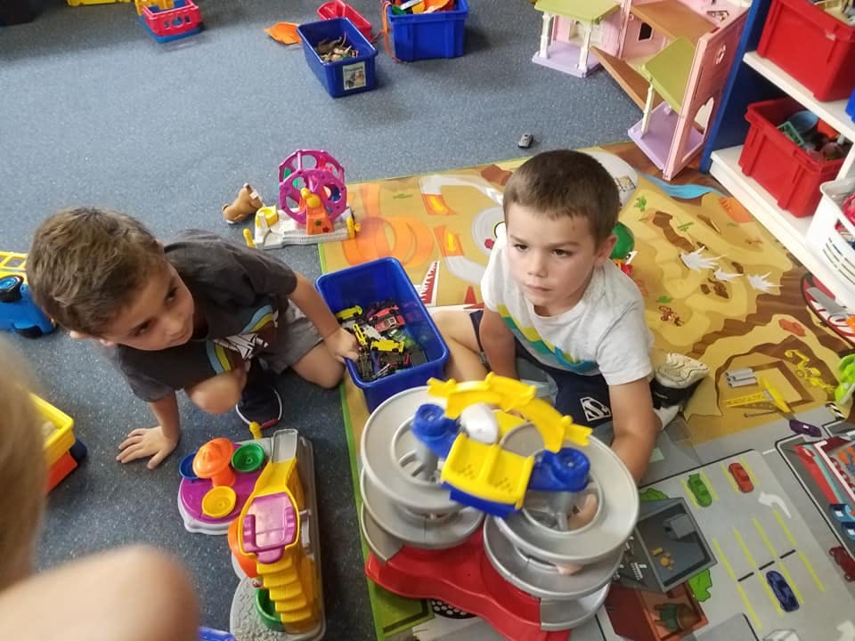 Two children playing with toys on a rug