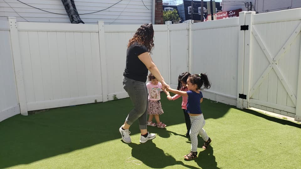 Person holding hands with two children in a fenced yard