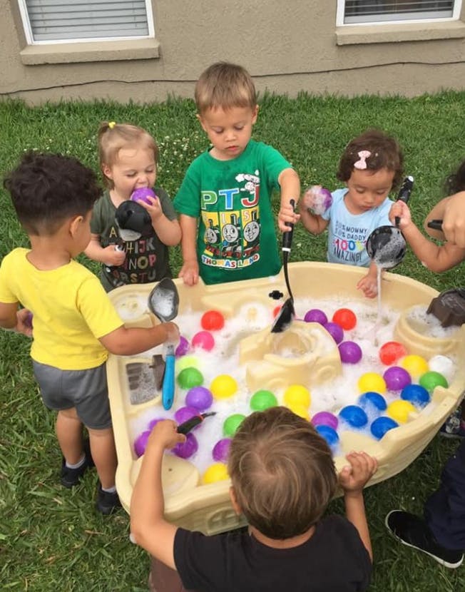 Children playing with a water table filled with colorful balls and bubbles