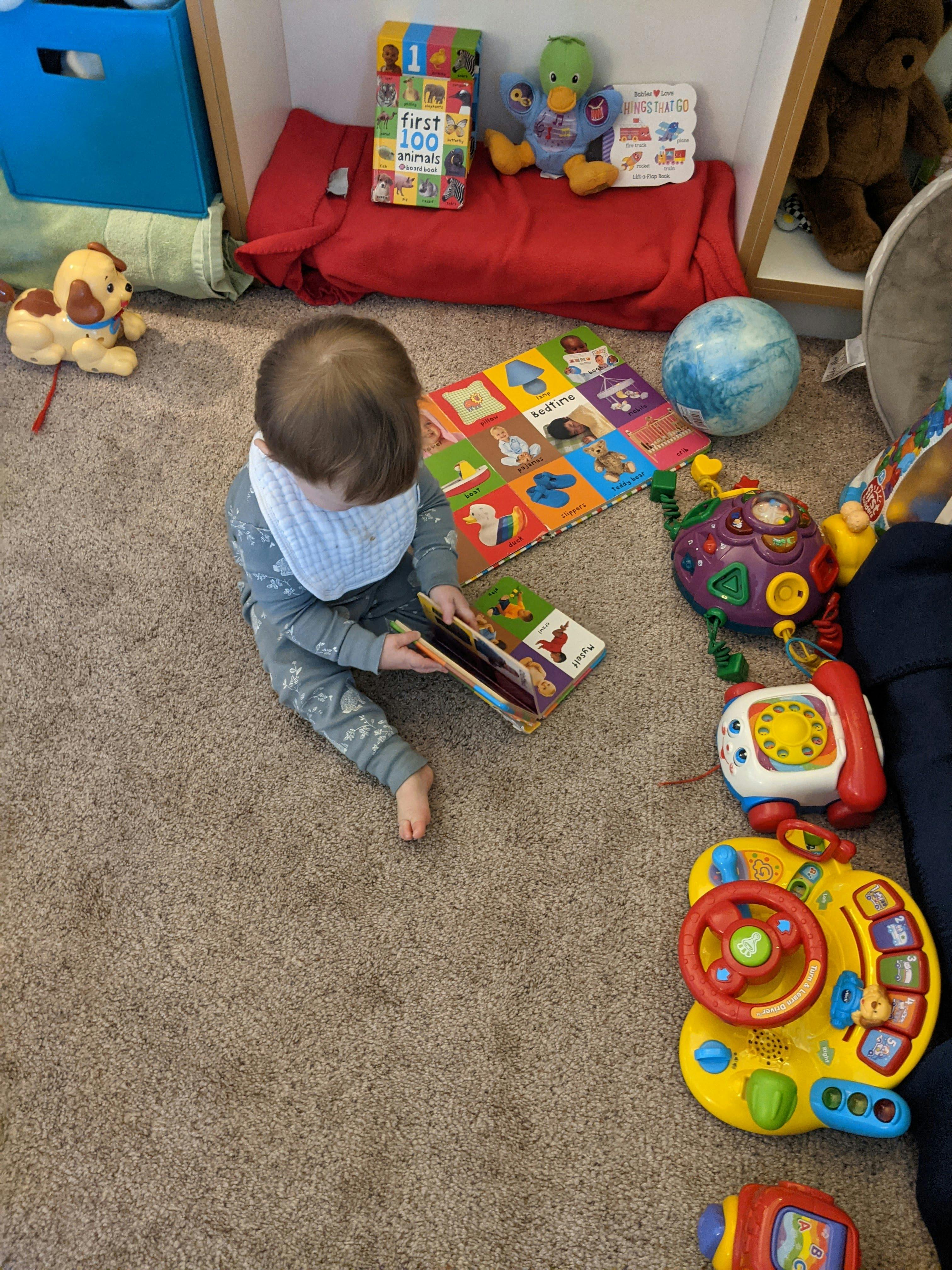 Child sitting on carpet, looking at a book